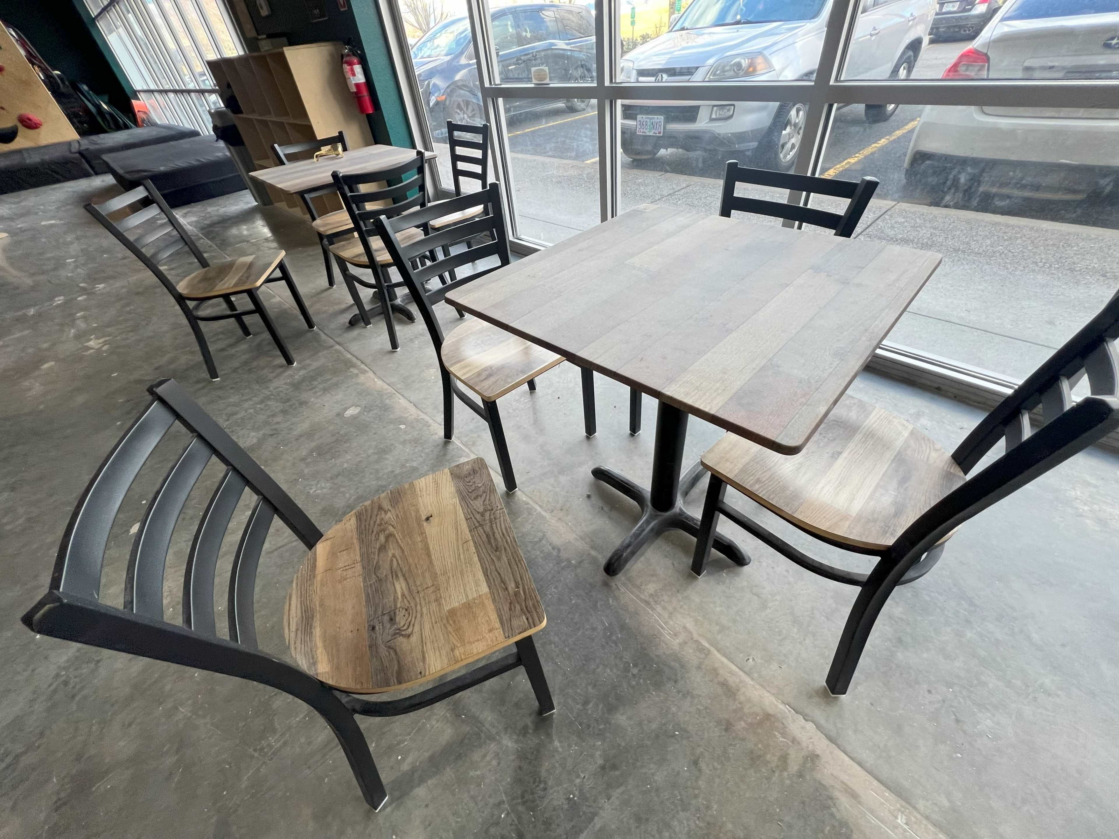 A wooden table surrounded by several metal and wooden chairs is situated in a well-lit interior space.