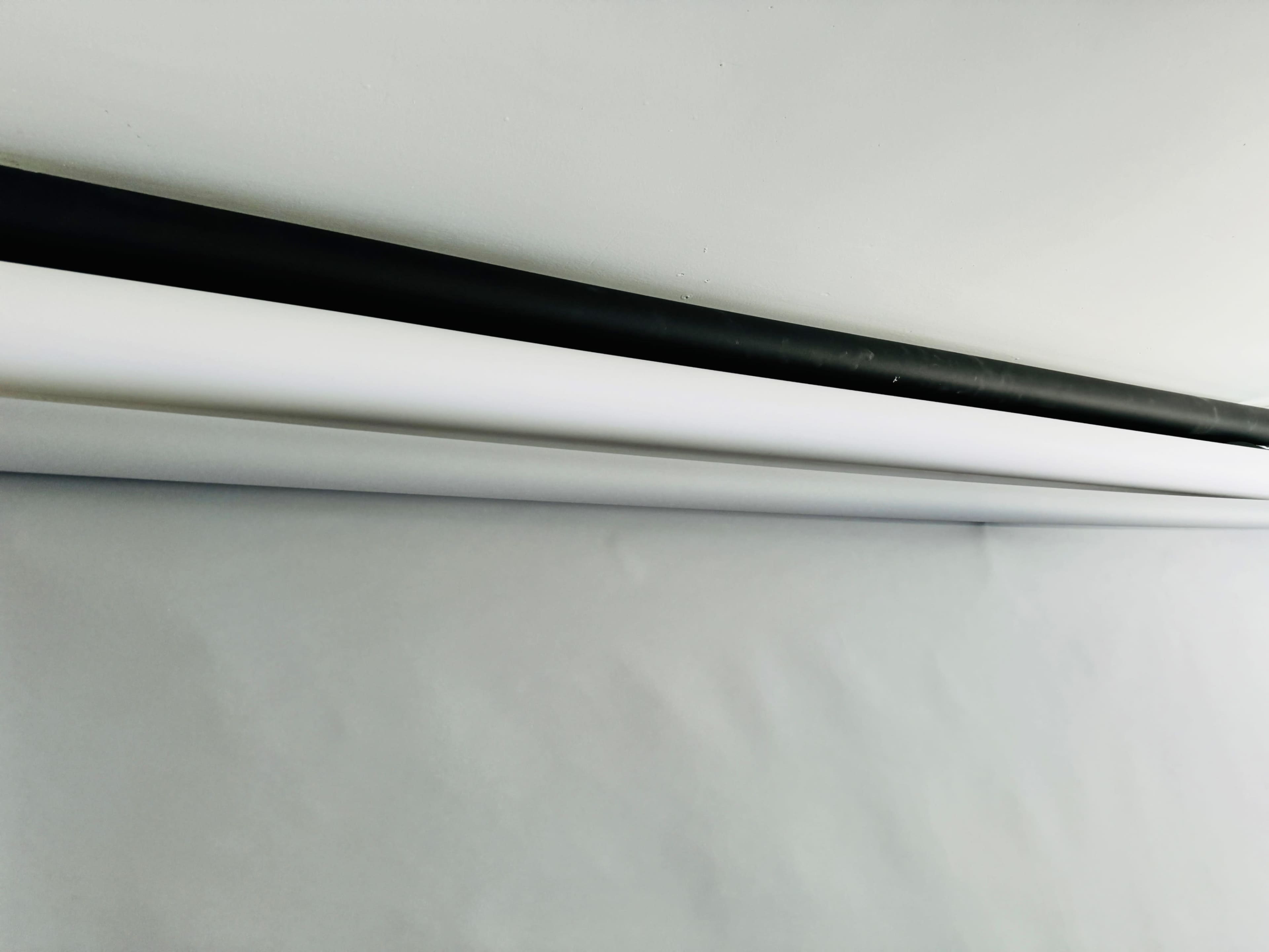 A black roller and a white roll of paper mounted on a gray wall.
