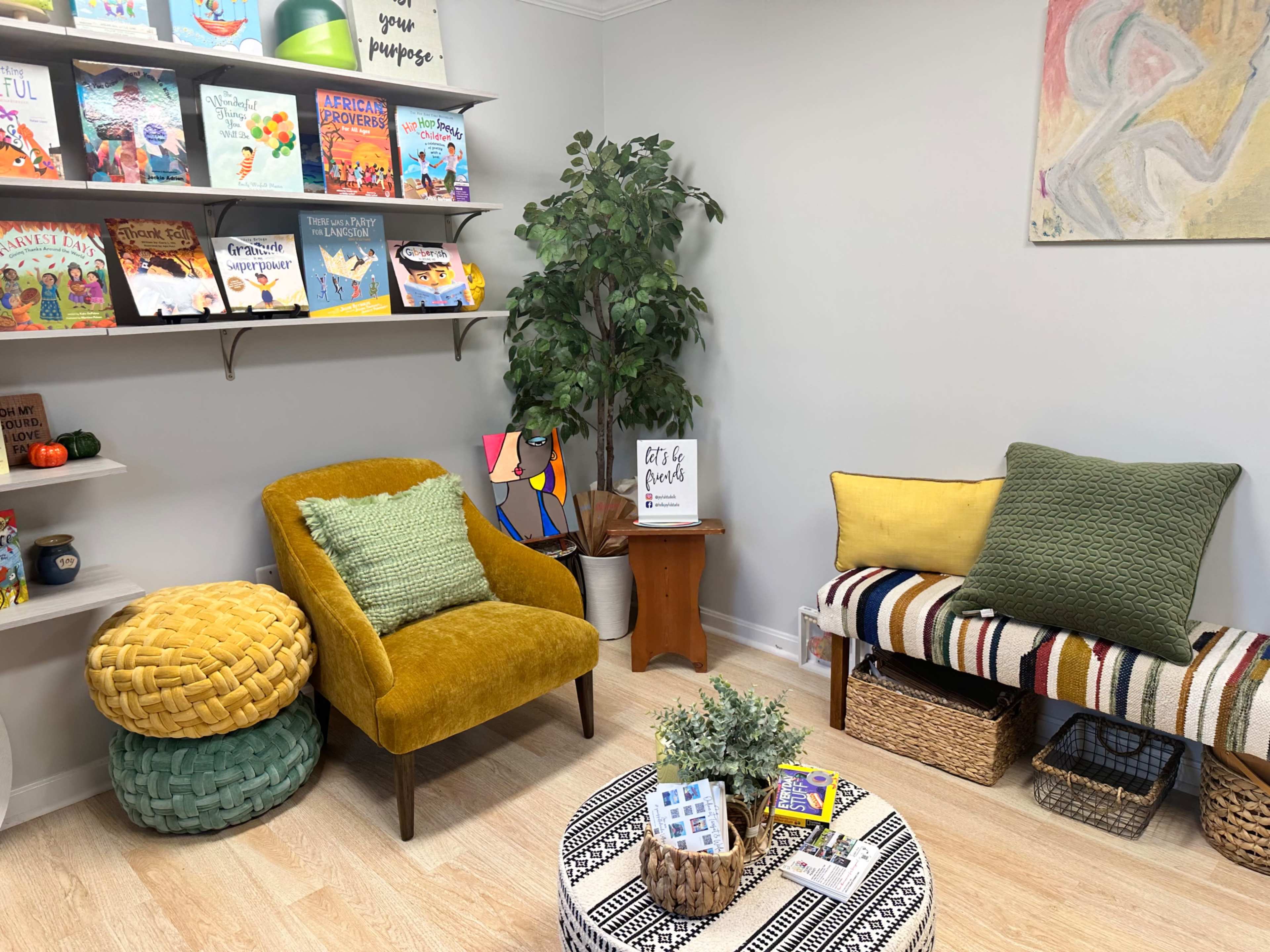 A cozy reading nook with two chairs, a small round table, shelves filled with colorful books, and decorative plants.