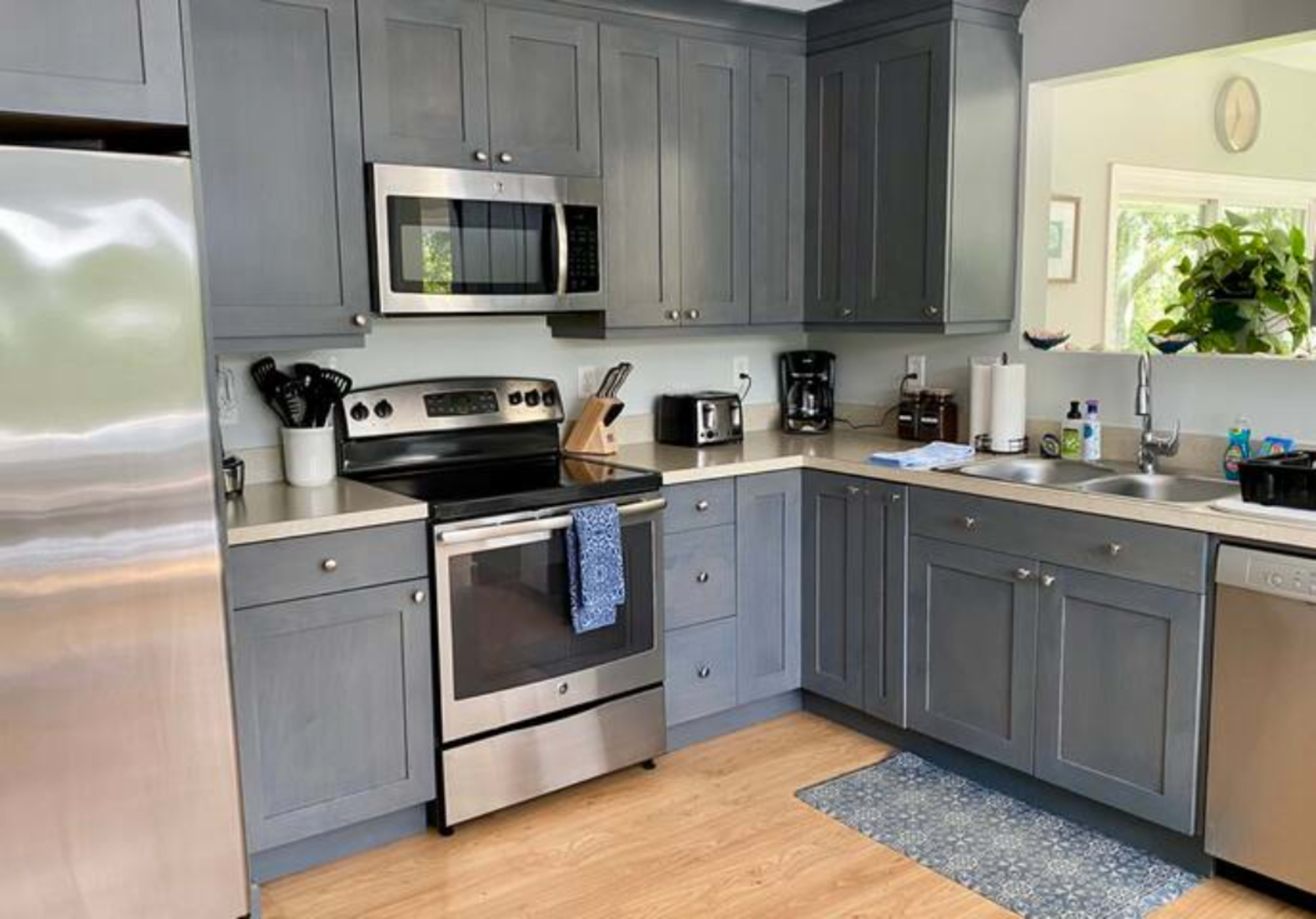 A modern kitchen features gray cabinetry, stainless steel appliances, and a countertop with various small appliances and utensils.