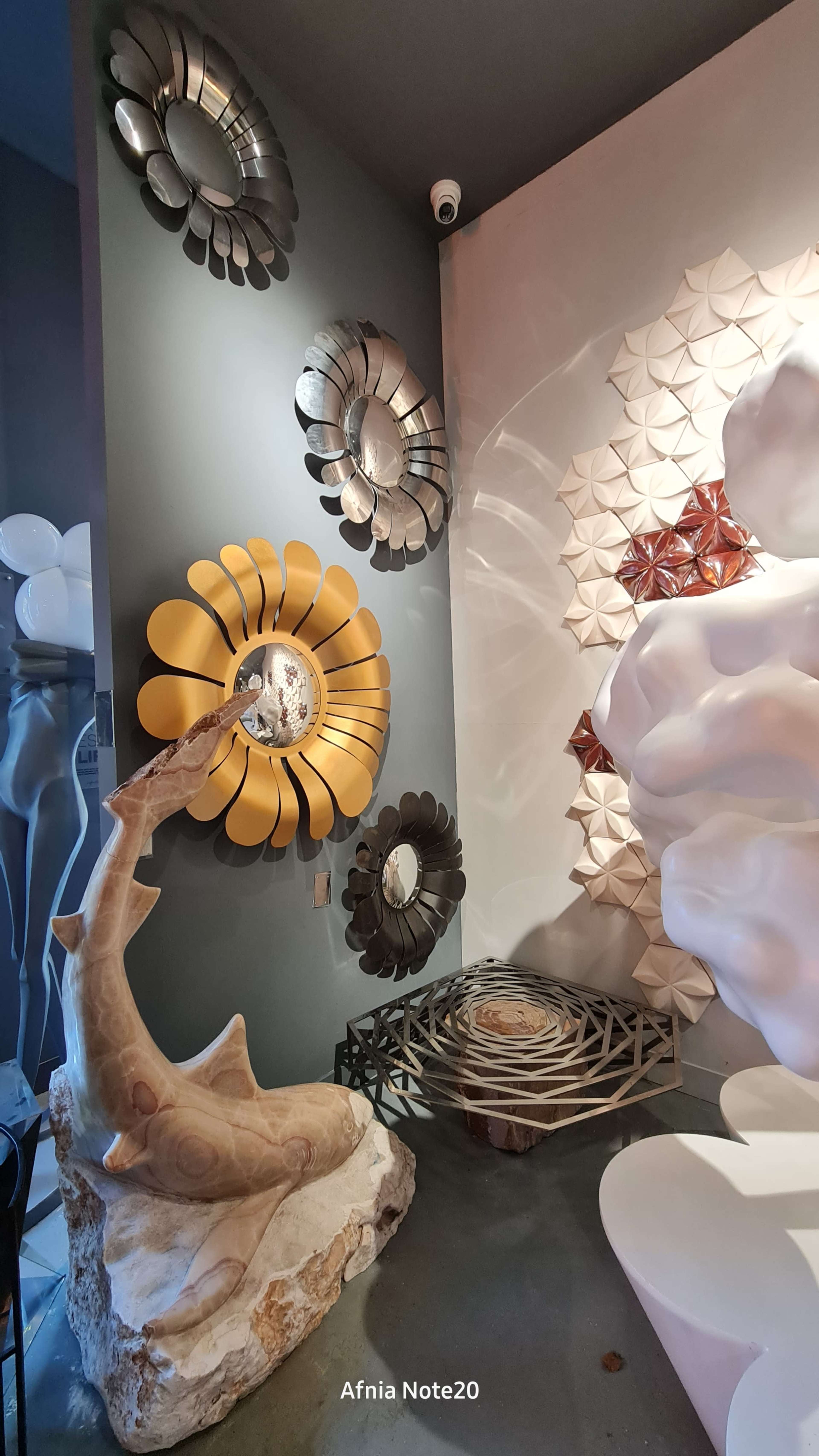 The scene features a corner with decorative mirrors resembling flowers on the walls, a sculptural piece resembling a fish or horn, and abstract wall designs.