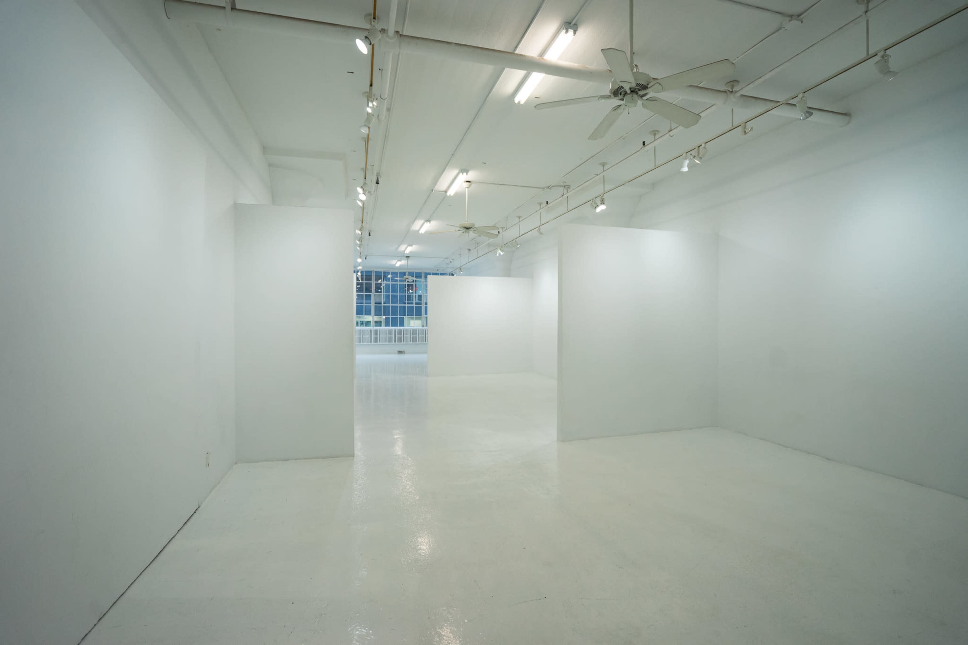 A minimalist, empty gallery space with white walls and polished floors.