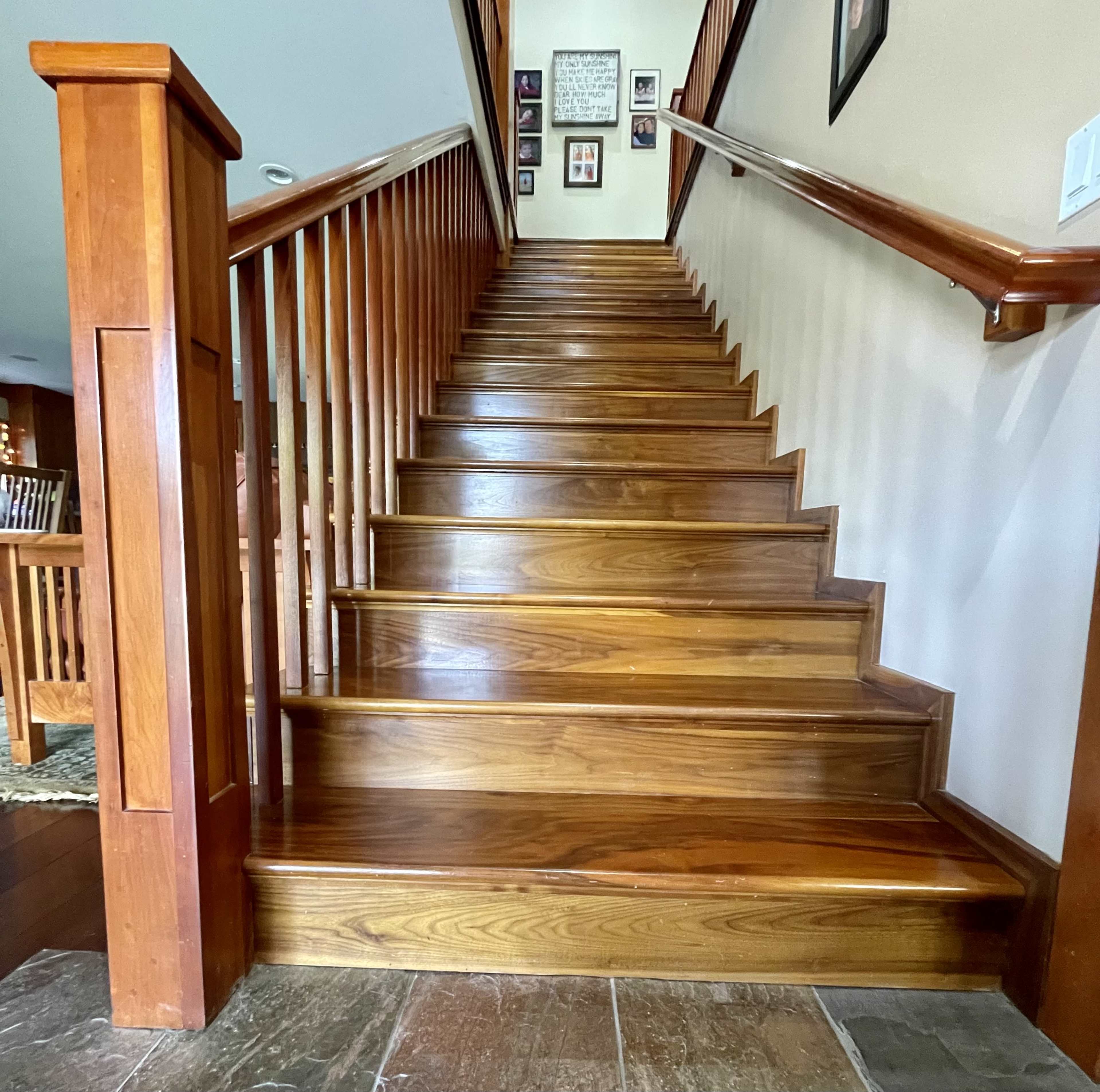 A wooden staircase with polished steps leading upward in a well-lit hallway.