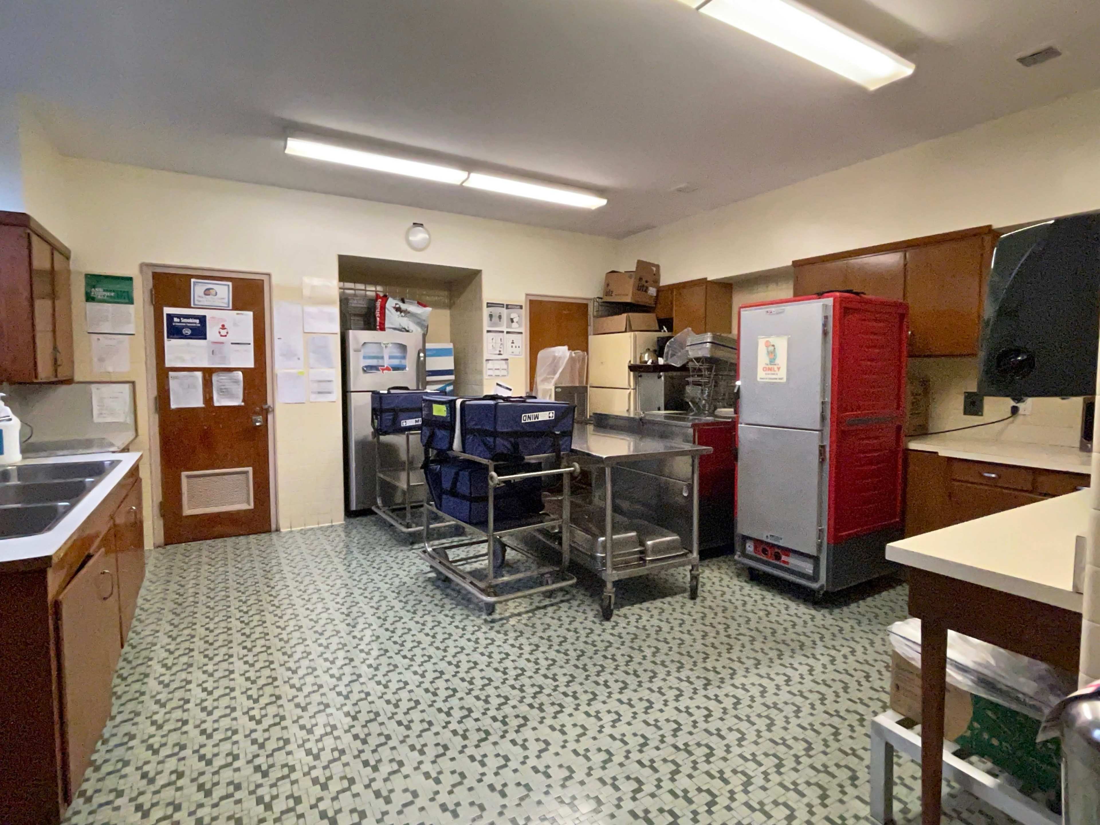 The kitchen features stainless steel equipment, wooden cabinetry, and patterned tile flooring.