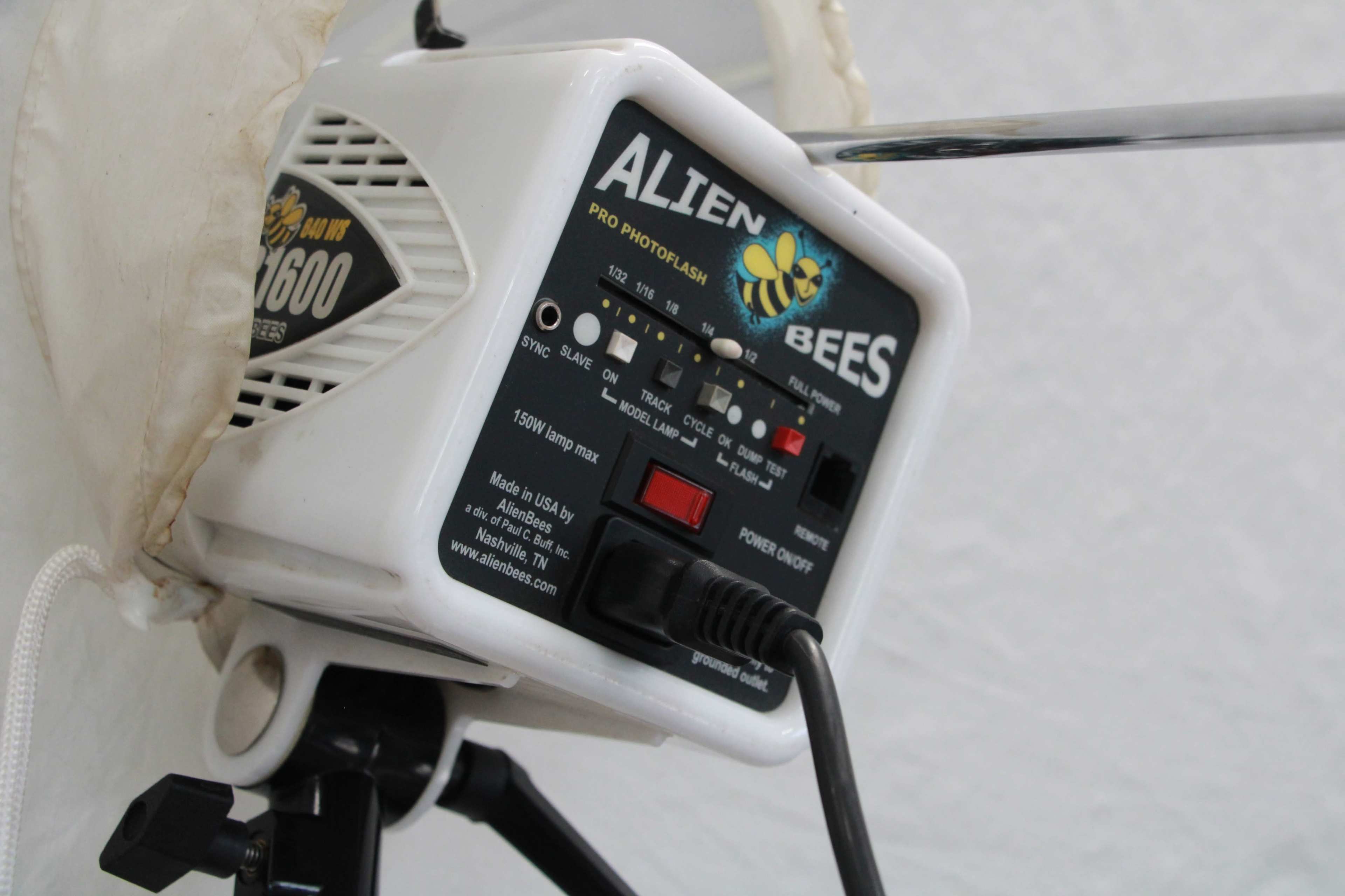 The image shows a white Alien Bees B1600 studio flash unit mounted on a black tripod.