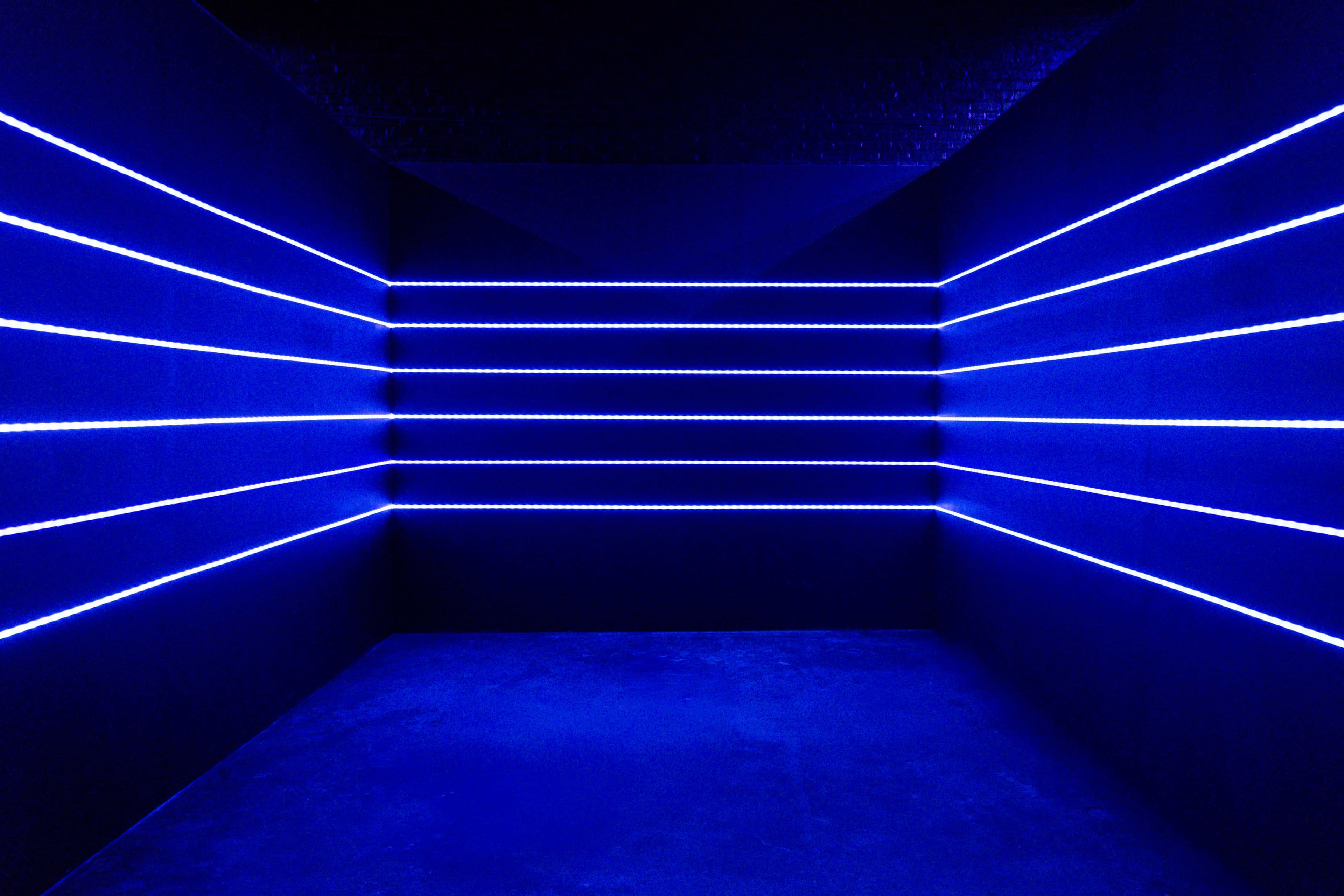 The image shows a dimly lit room with blue LED light strips arranged horizontally along the walls.