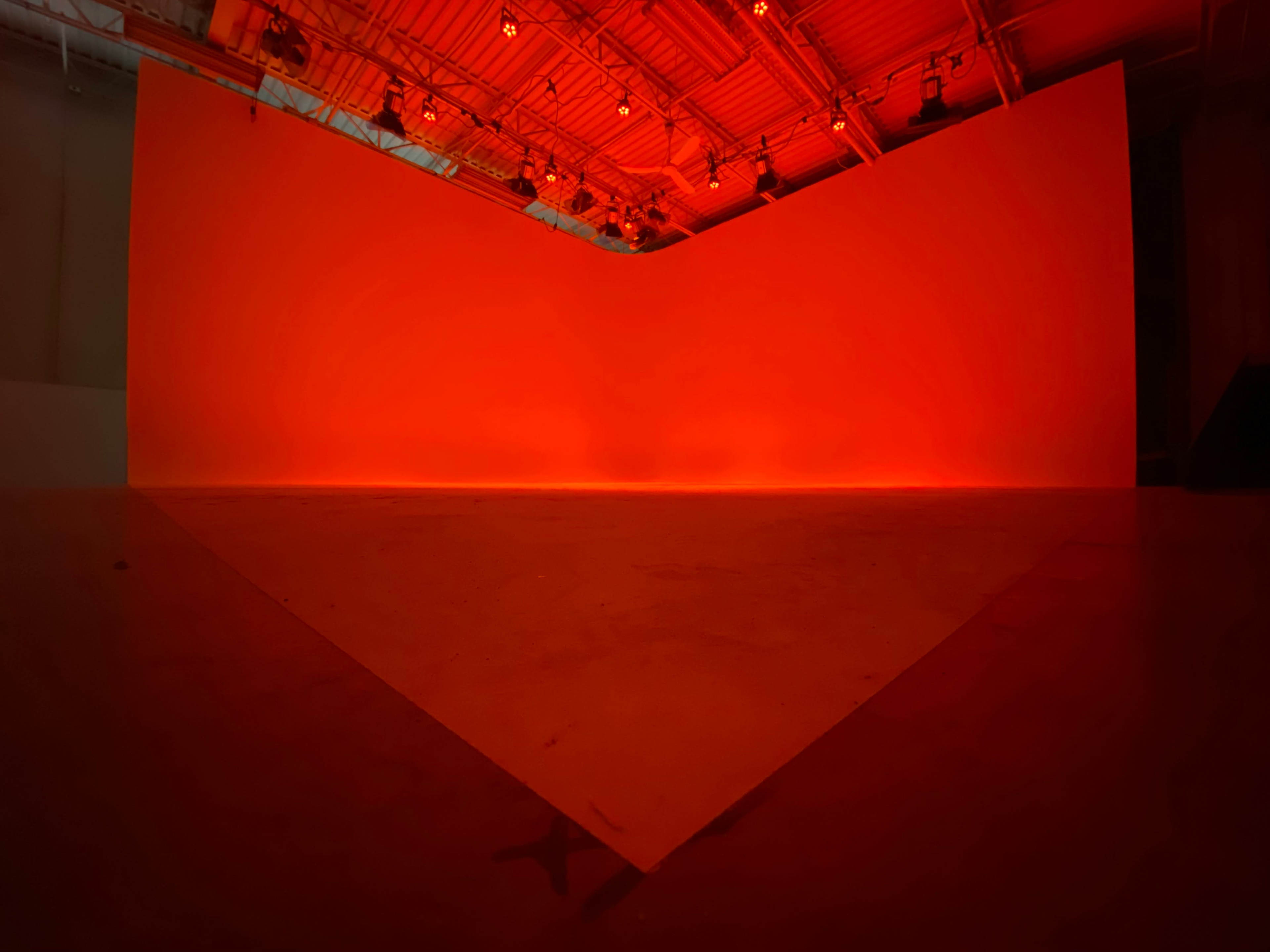 A large, empty space with a triangular lighted area and red-colored walls.