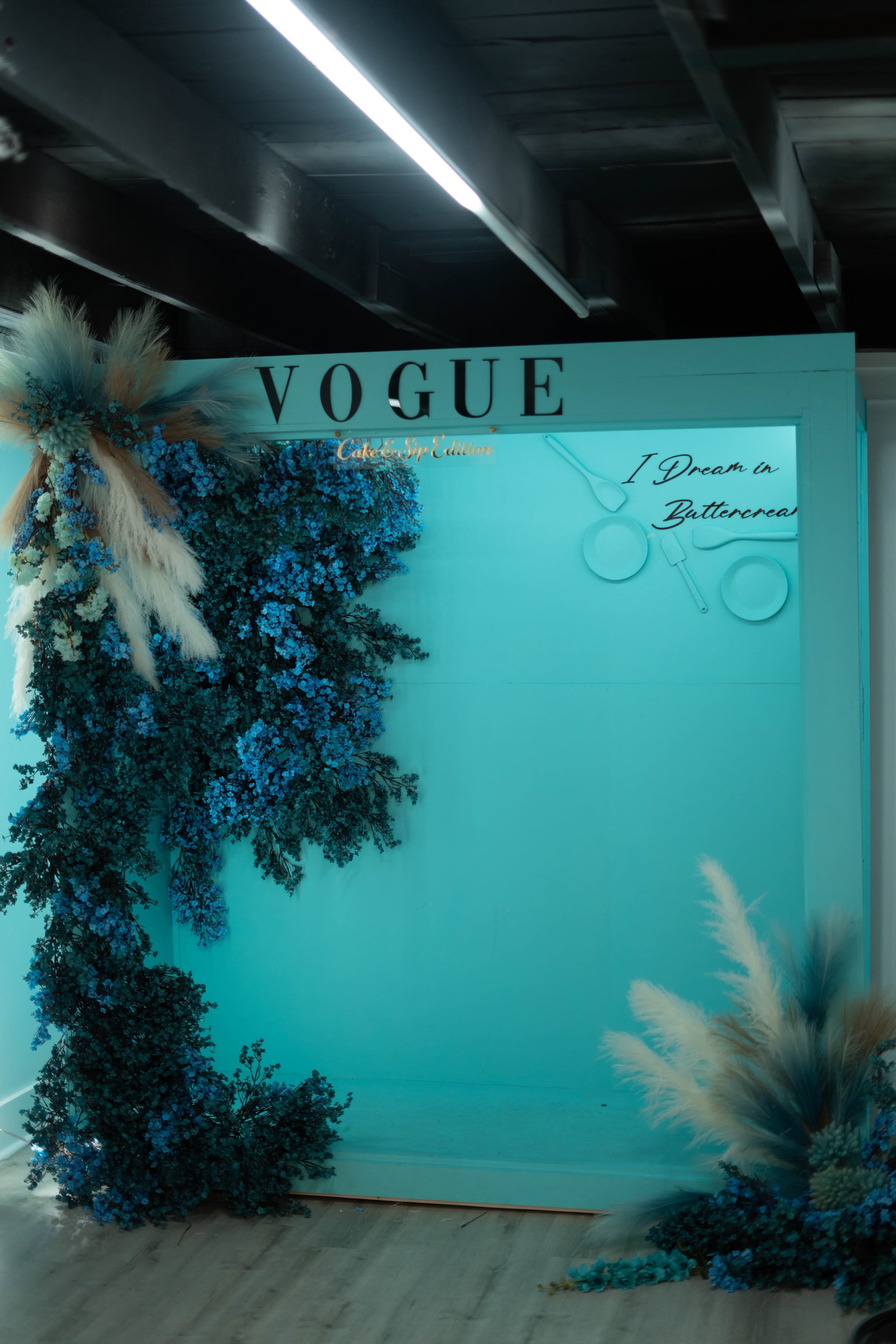 A vibrant backdrop with blue flowers and pampas grass, alongside the word "VOGUE" and a sign that reads "I Dream of Butterflies."