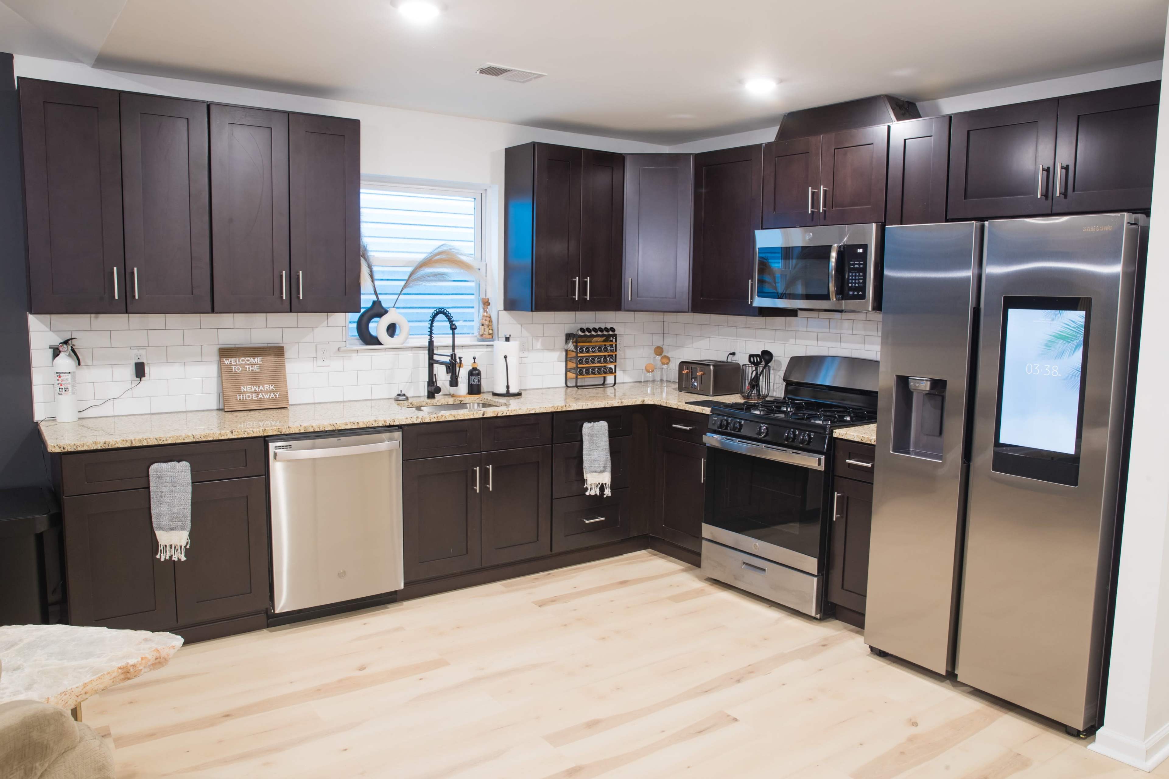 The kitchen features dark wooden cabinets, stainless steel appliances, and a light-colored countertop with a tiled backsplash.