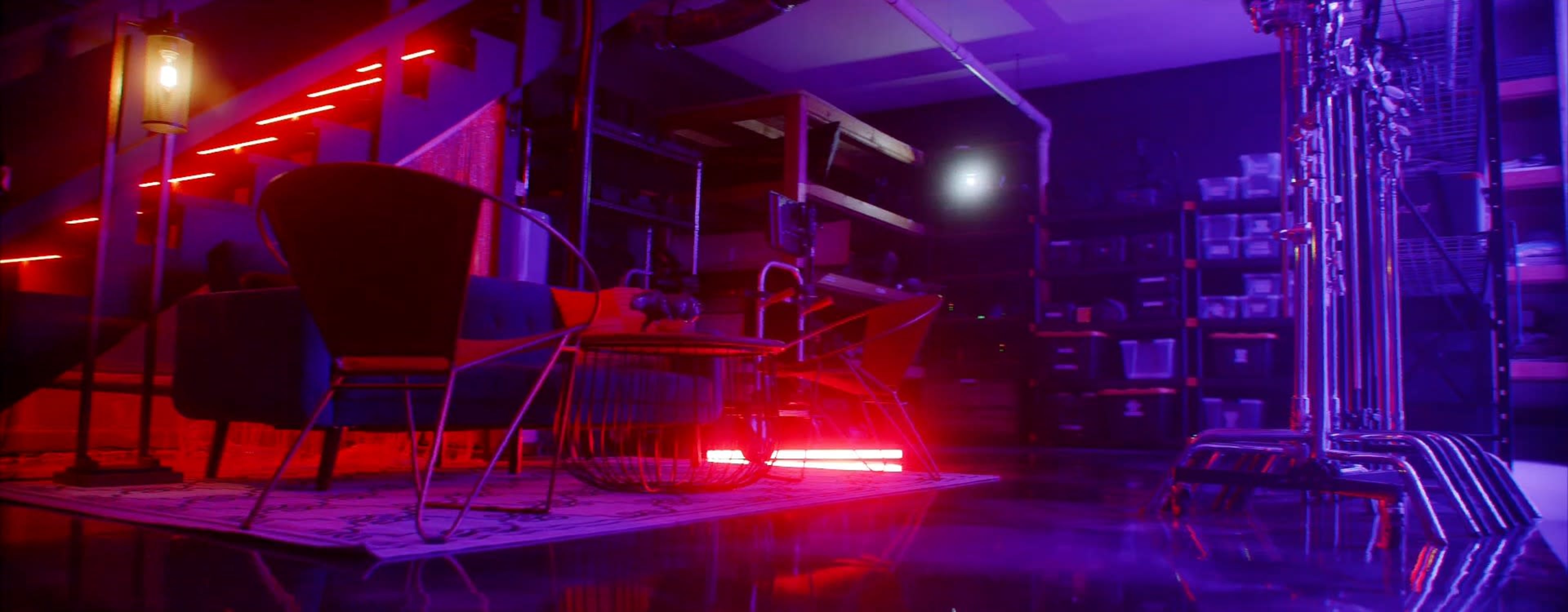 The image shows an interior space featuring modern furniture, including two chairs, illuminated by colorful lighting and surrounded by storage shelves filled with various items.