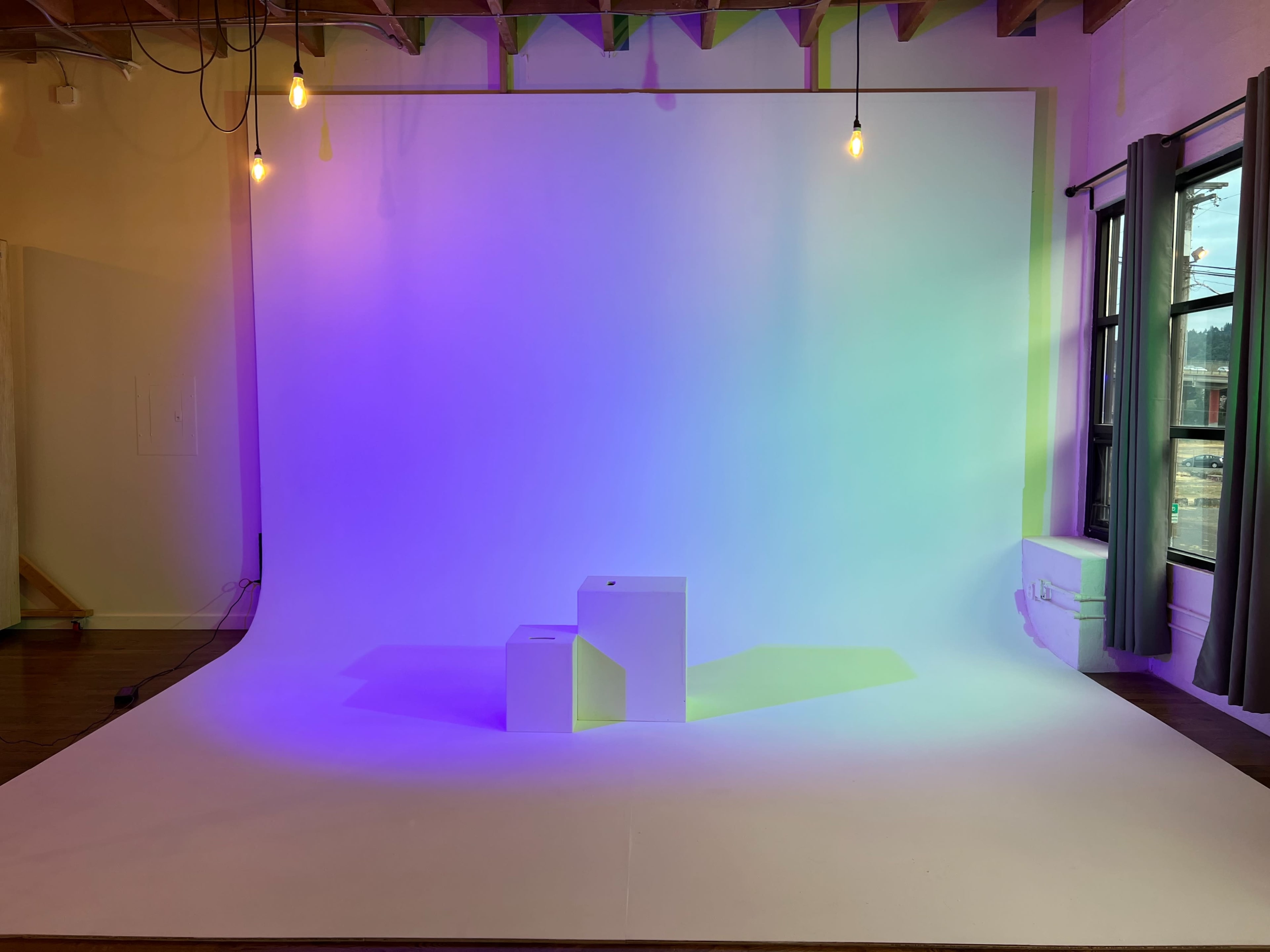 The image shows a well-lit studio space with a gradient backdrop and two white pedestals positioned in front of it.