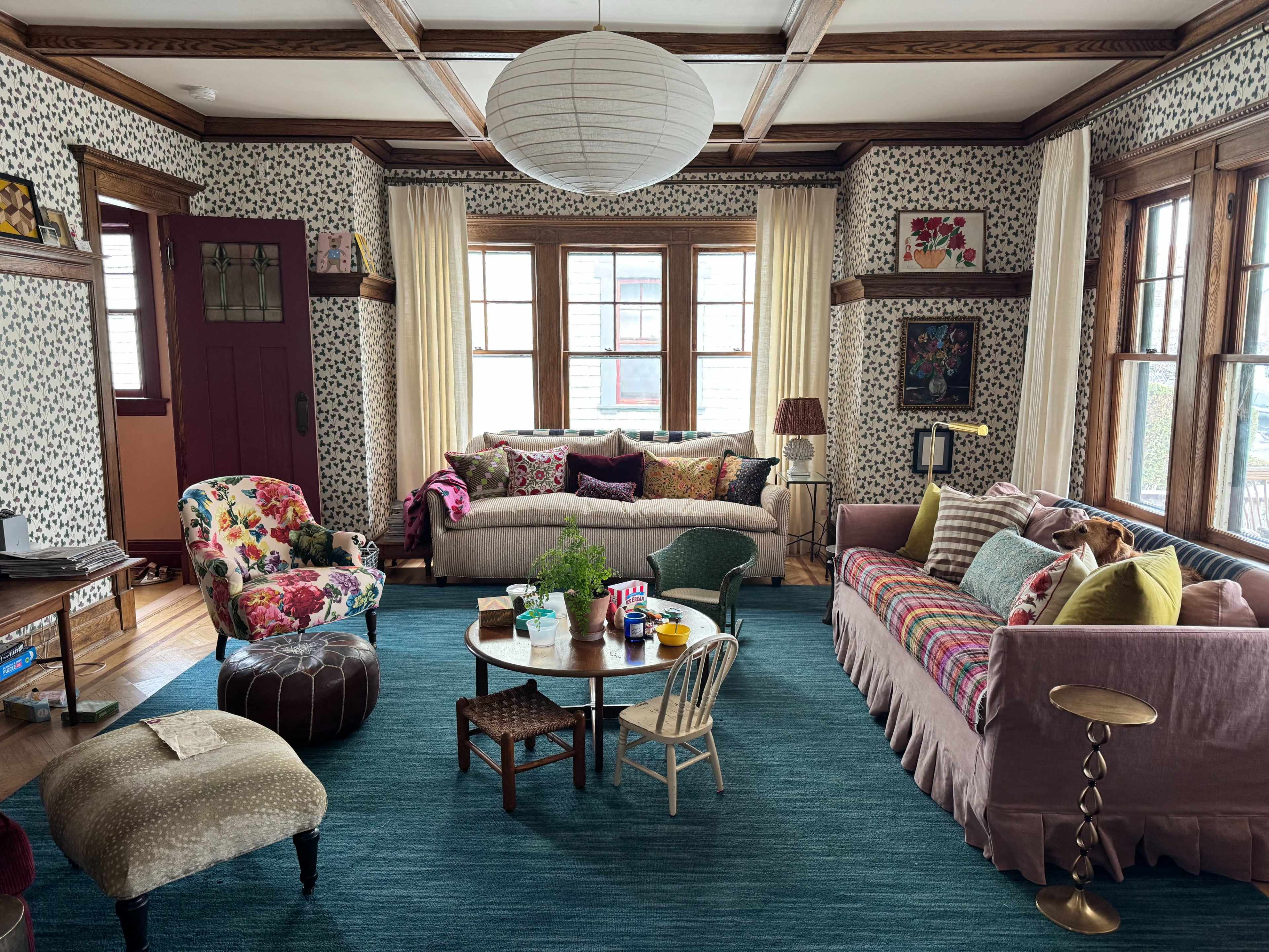 The room features a mix of colorful furniture and decorative elements, with a central coffee table surrounded by seating on a vibrant rug.