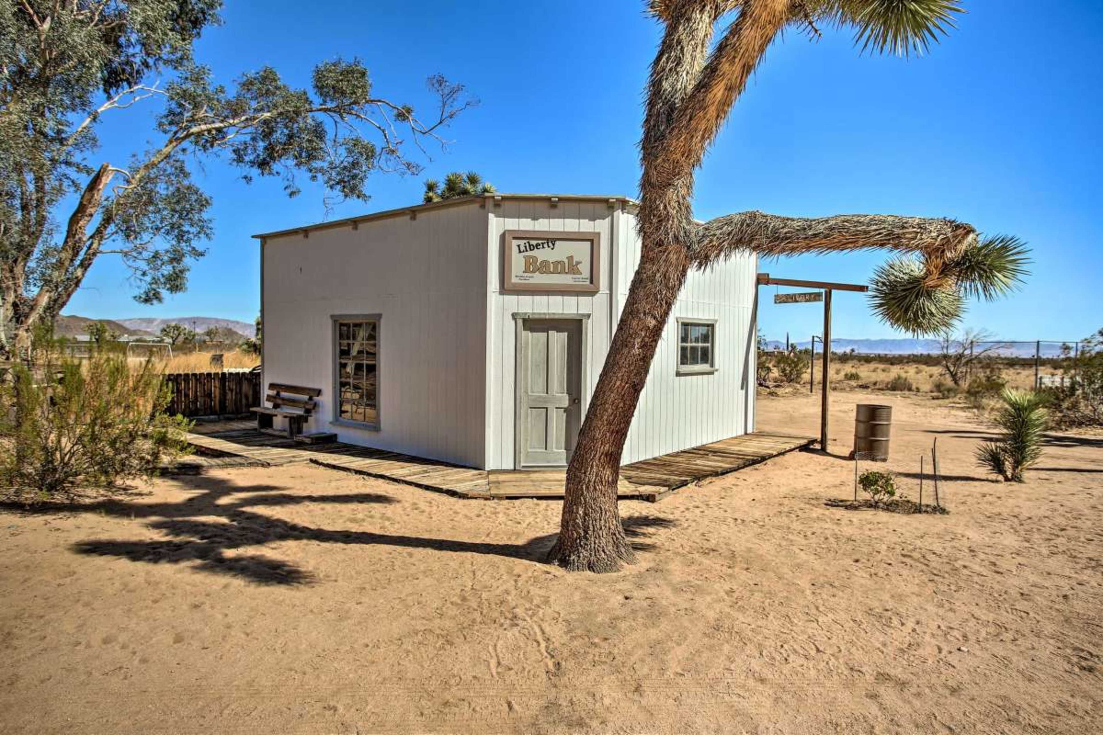 A small, white building labeled "Liberty Bank" surrounded by desert vegetation and sandy terrain.
