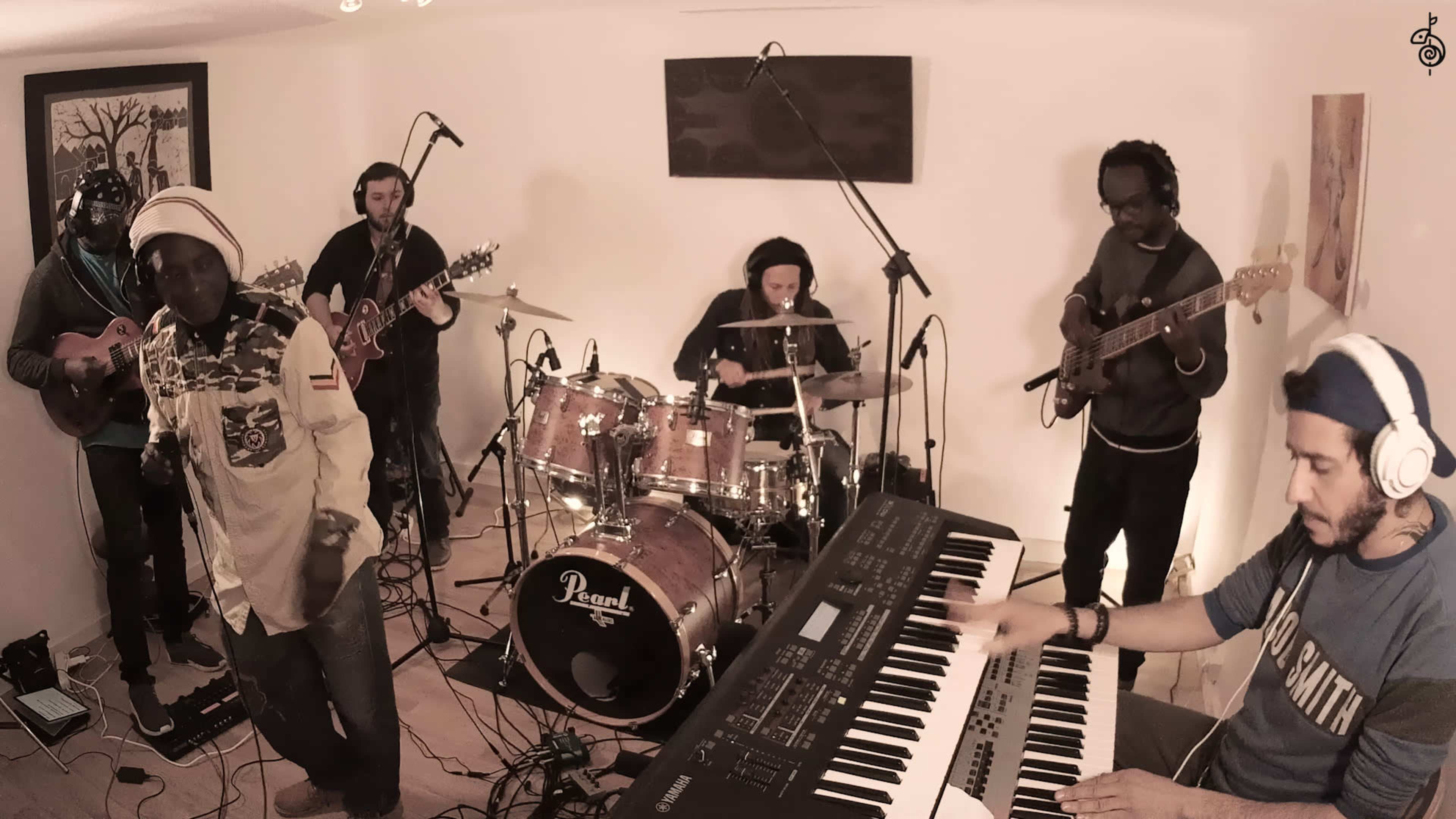 A group of musicians performs together in a studio, with a vocalist, guitarists, a bassist, a drummer, and a keyboardist.