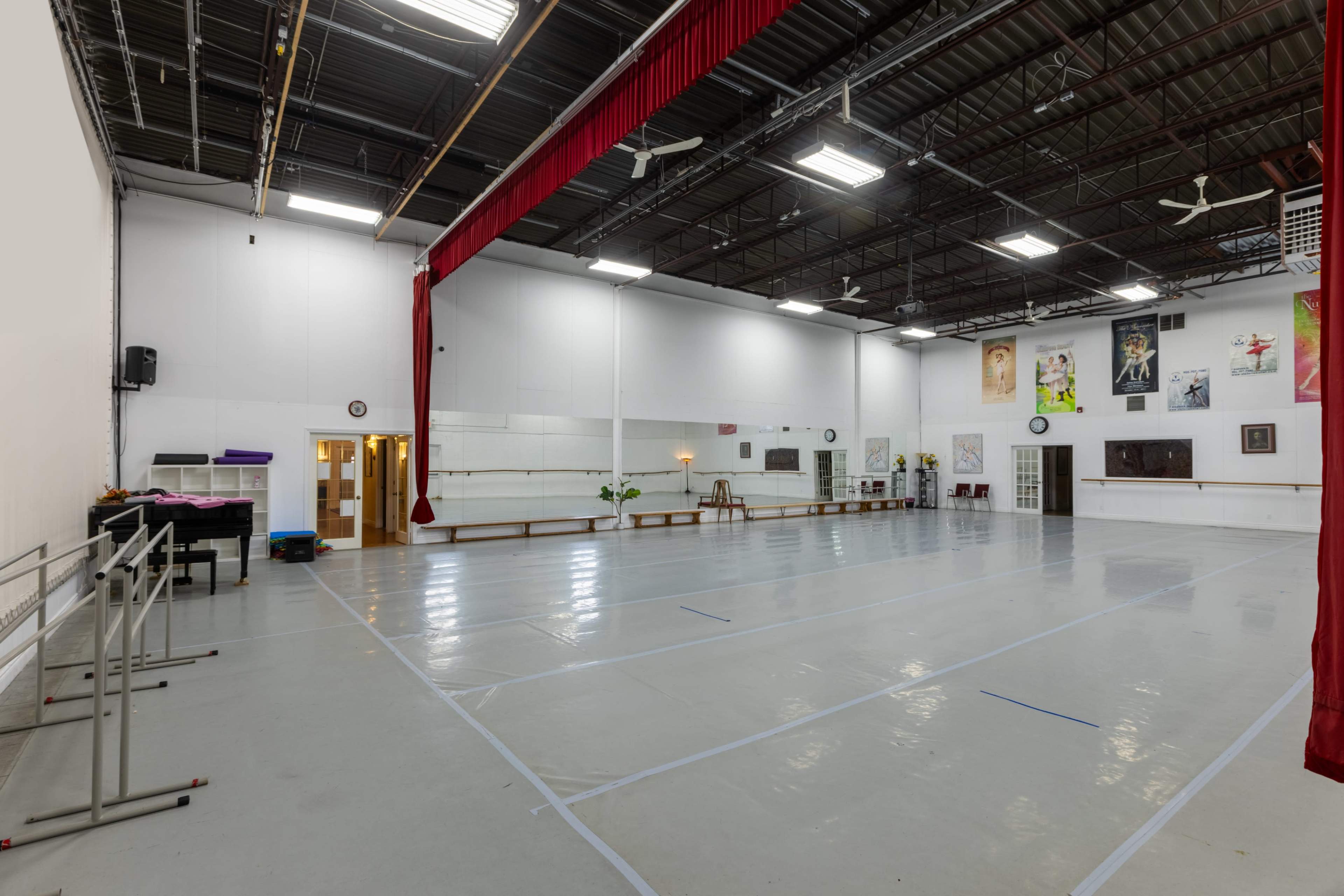 The image shows a spacious dance studio with a shiny floor, mirrors along one wall, and various artworks and decorations hanging on the other walls.