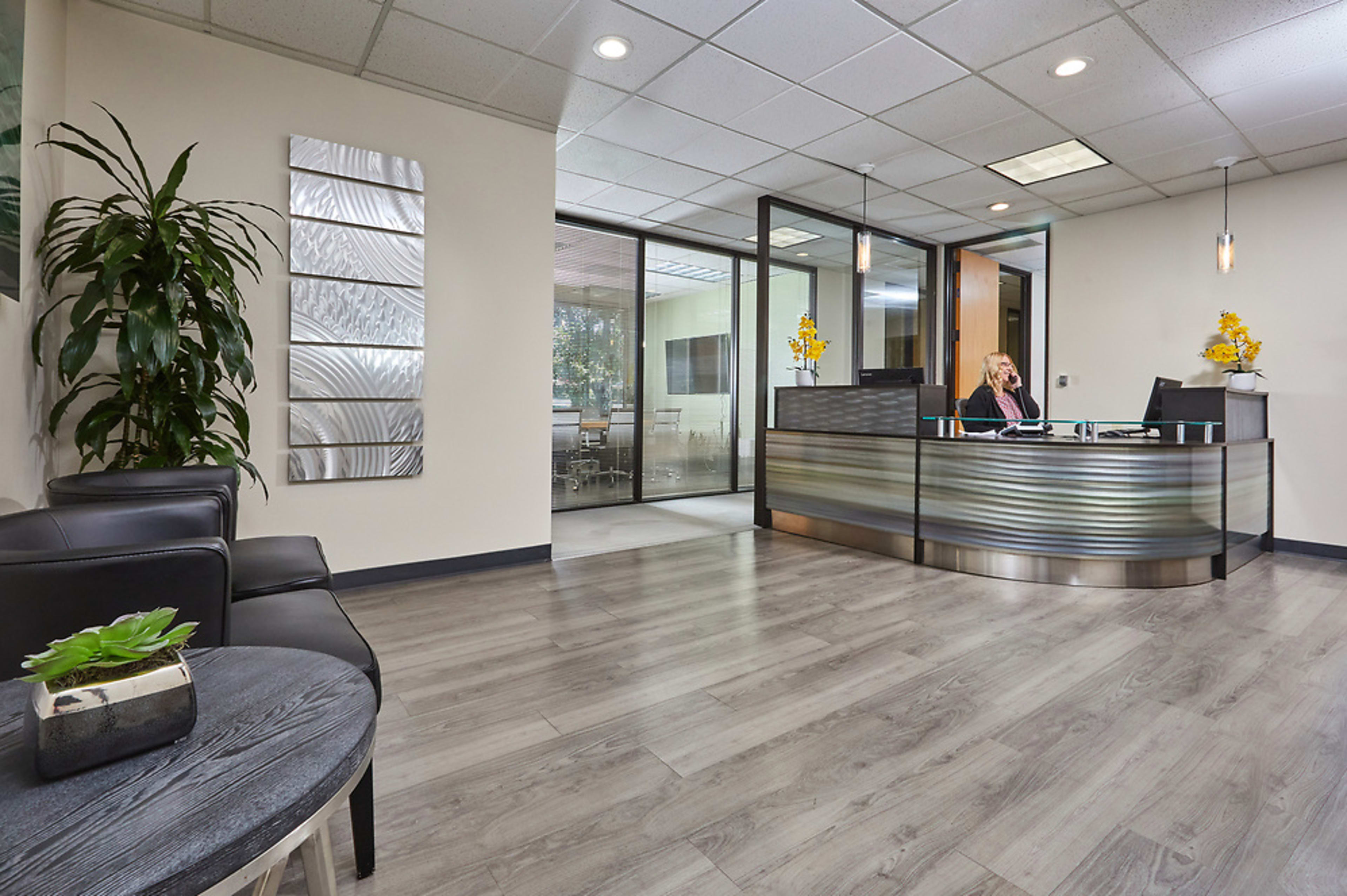 The image shows a modern office reception area with a front desk, large windows, and minimalist decor.