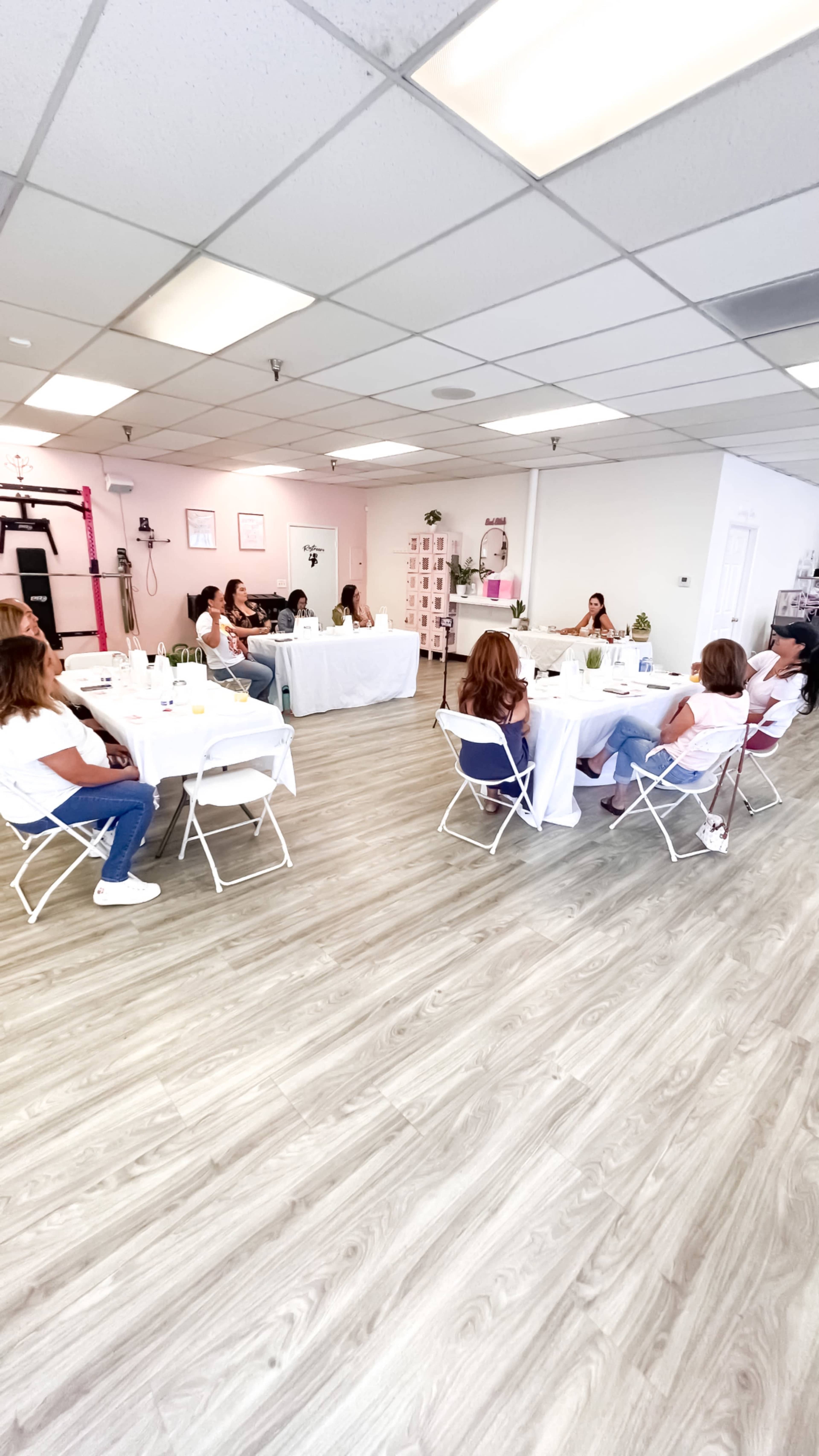 A group of people is seated around tables in a bright, spacious room, participating in a meeting or workshop.