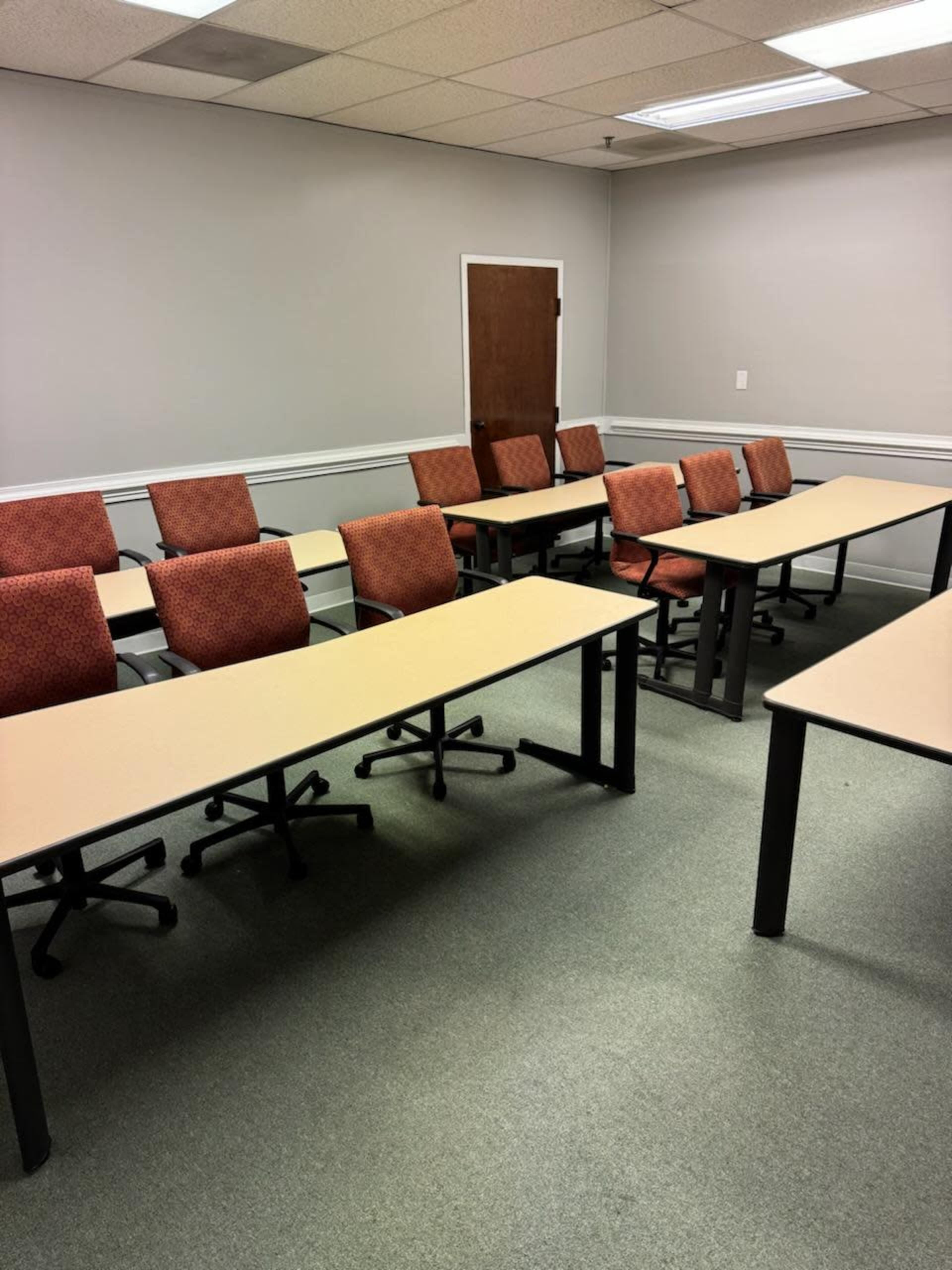 A classroom with several rows of empty tables and chairs arranged neatly.