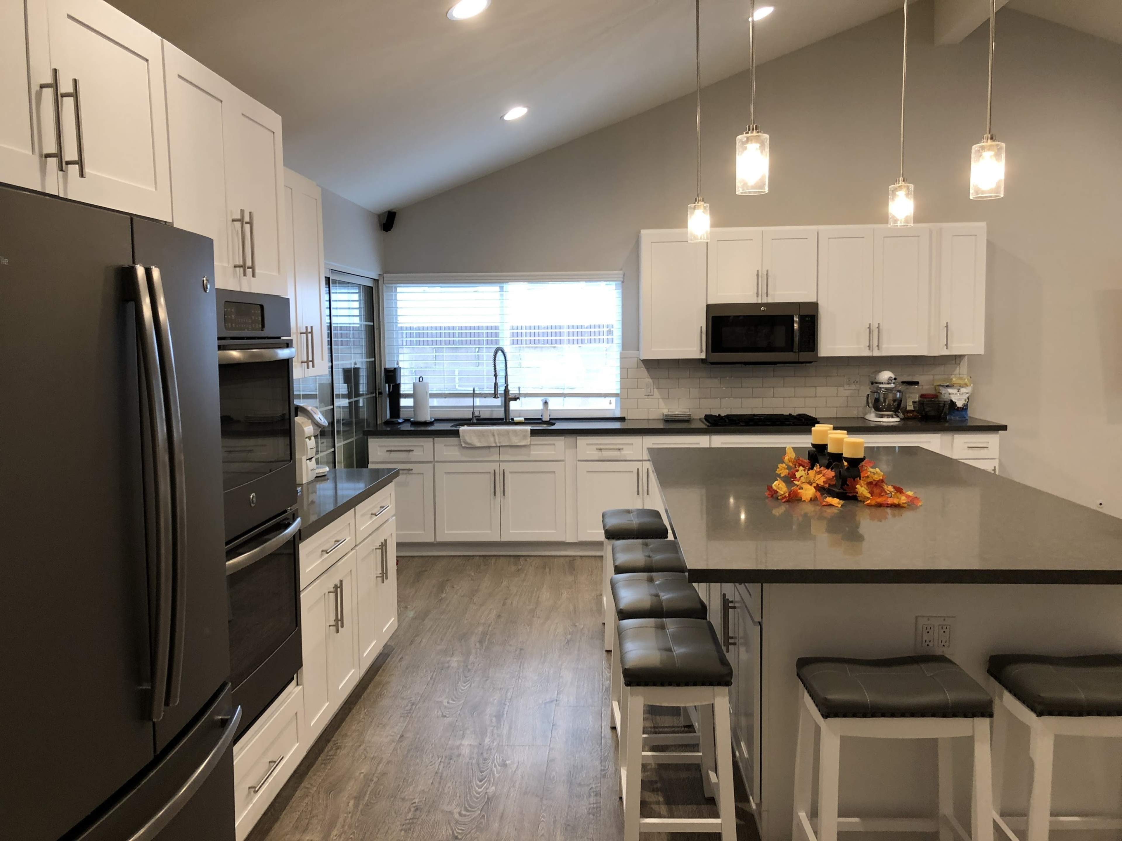 A modern kitchen with white cabinetry, stainless steel appliances, and a central island with seating and decorative candles.