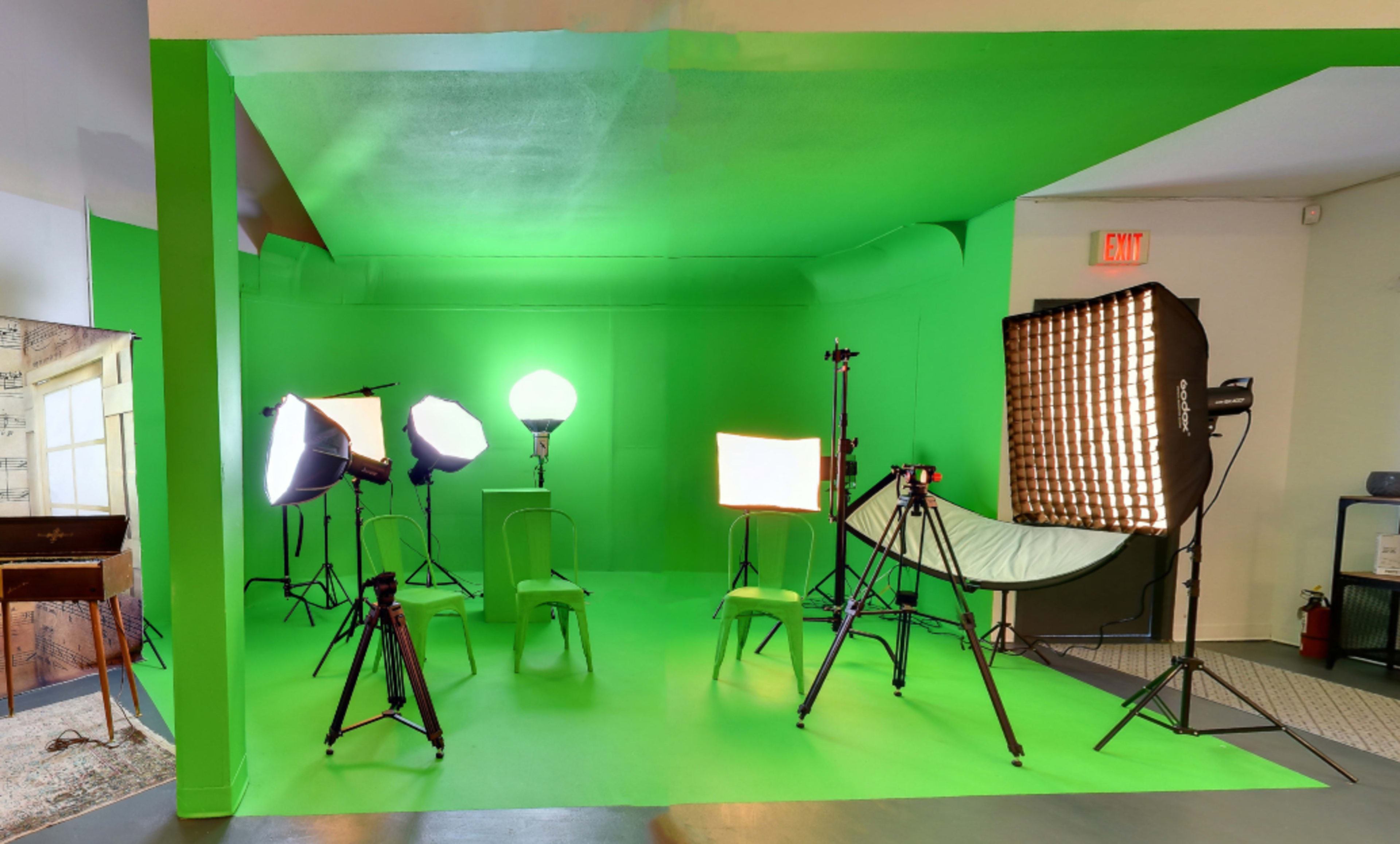 A photography studio equipped with multiple lighting setups and a green backdrop.