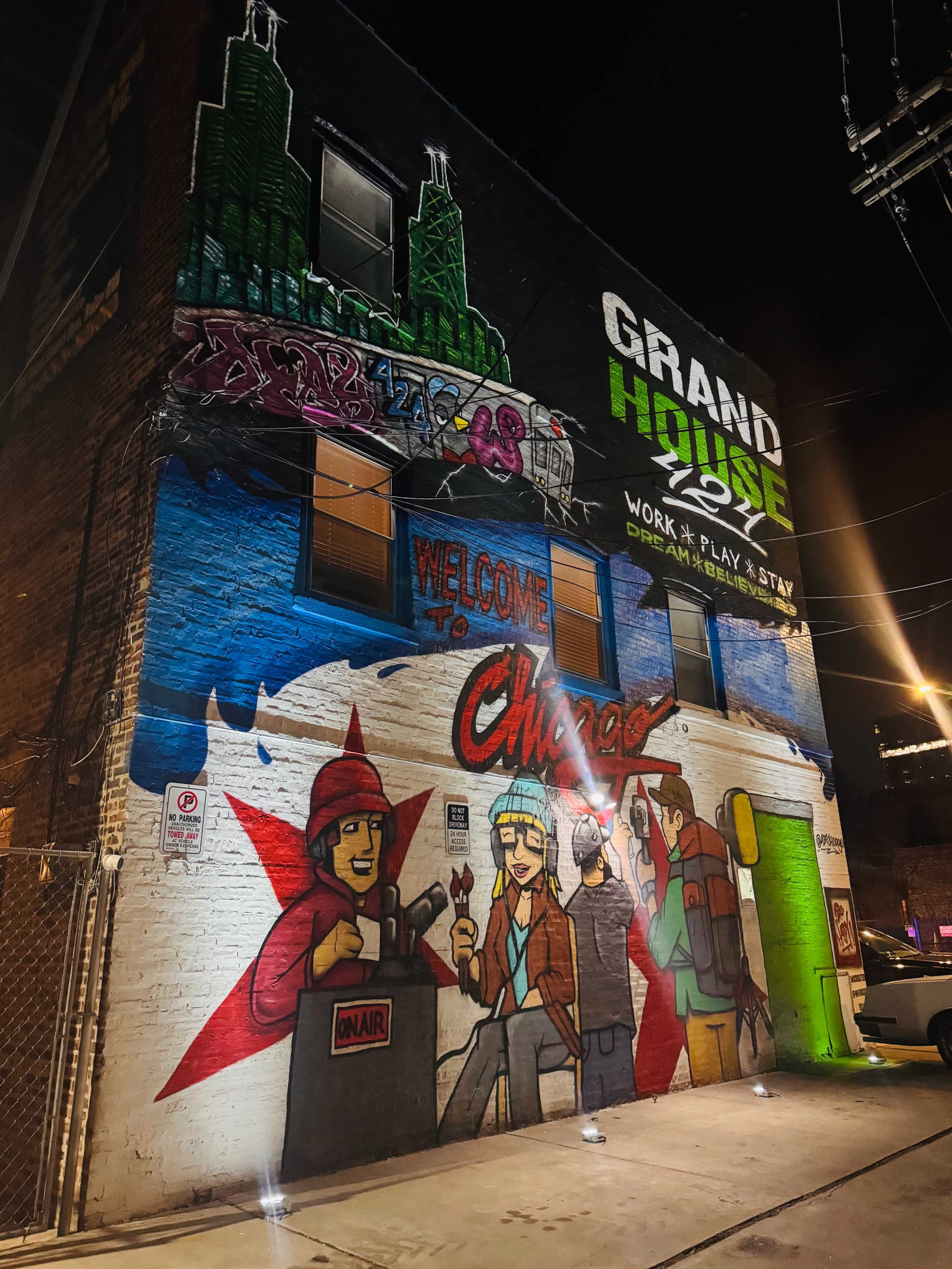 The image shows a colorful mural on the side of a building, featuring the words "Welcome to Chicago" alongside images of people and city landmarks.