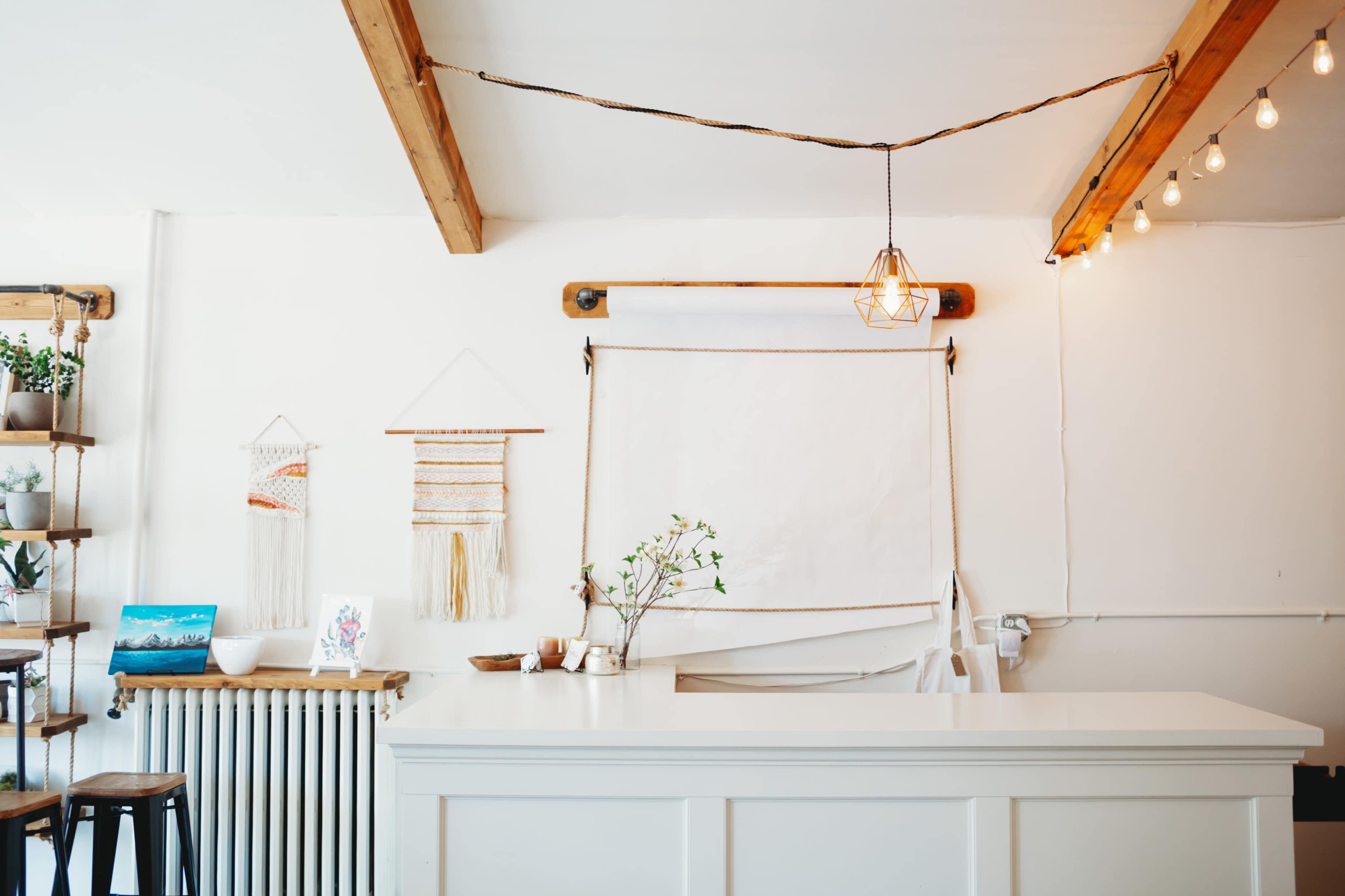 A bright interior features a white reception counter, wooden beams, and decorative wall hangings.