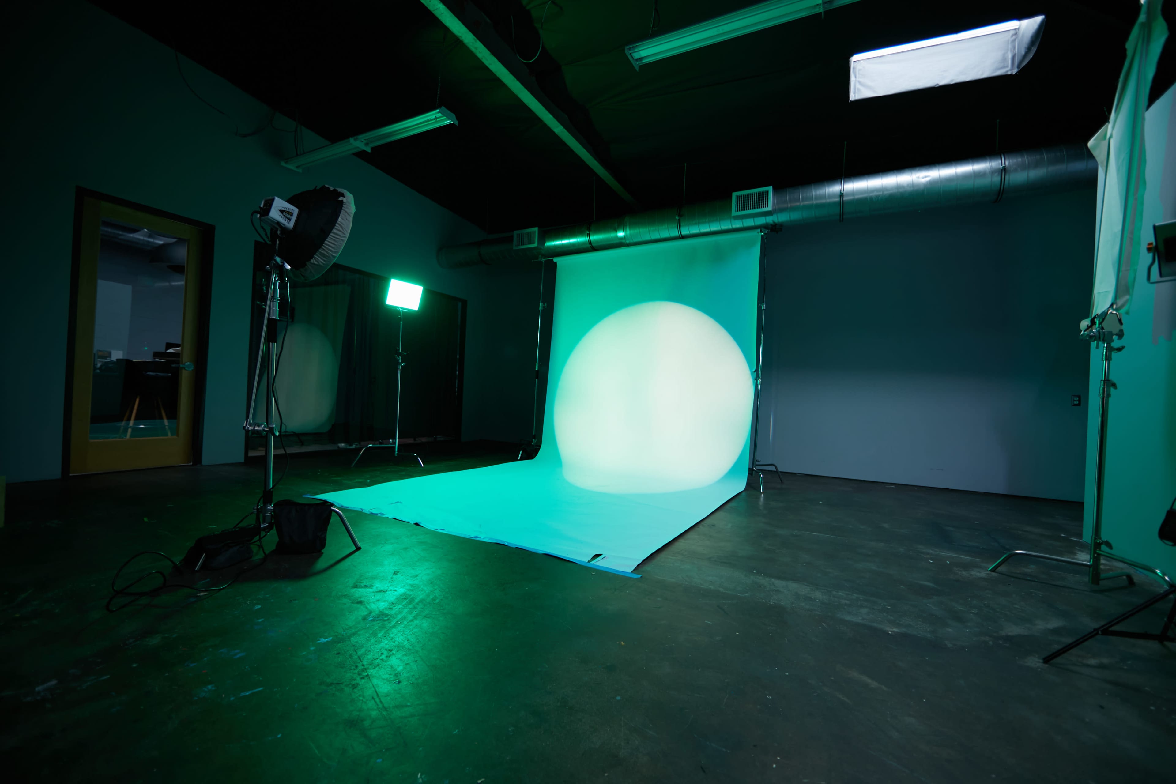 A photography studio features a backdrop with a large circular light and equipment set up for a photoshoot.