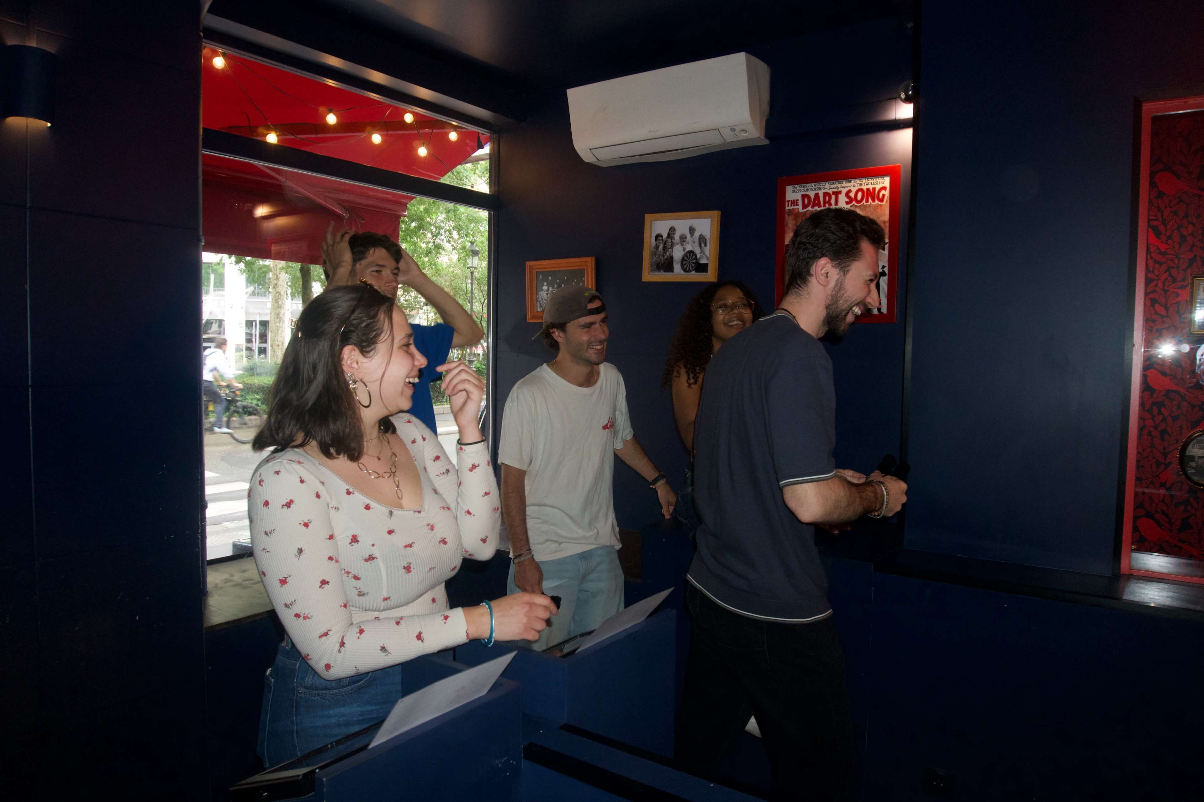 A group of five people stands in a colorful room, engaged in playful interaction.