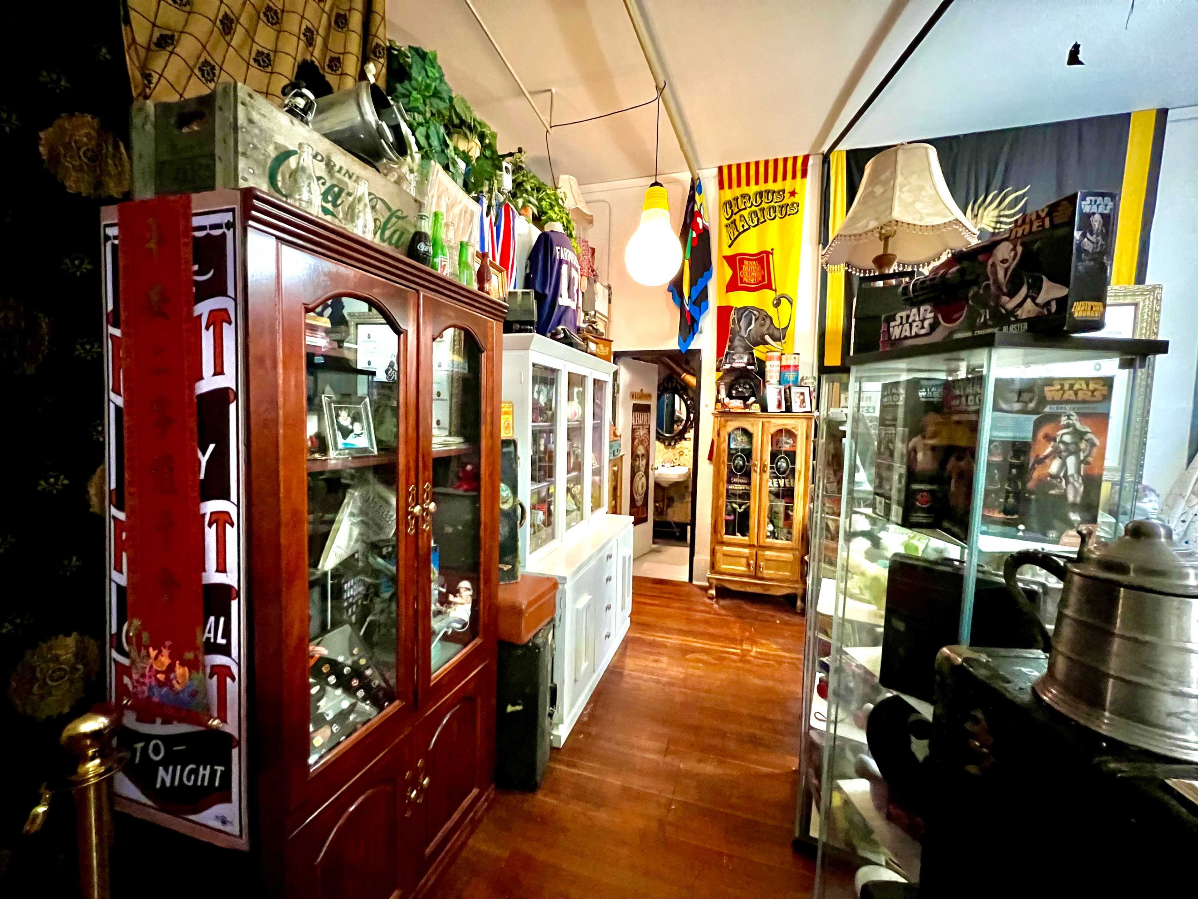 A narrow aisle lined with display cases containing various collectibles and memorabilia in a museum-like setting.
