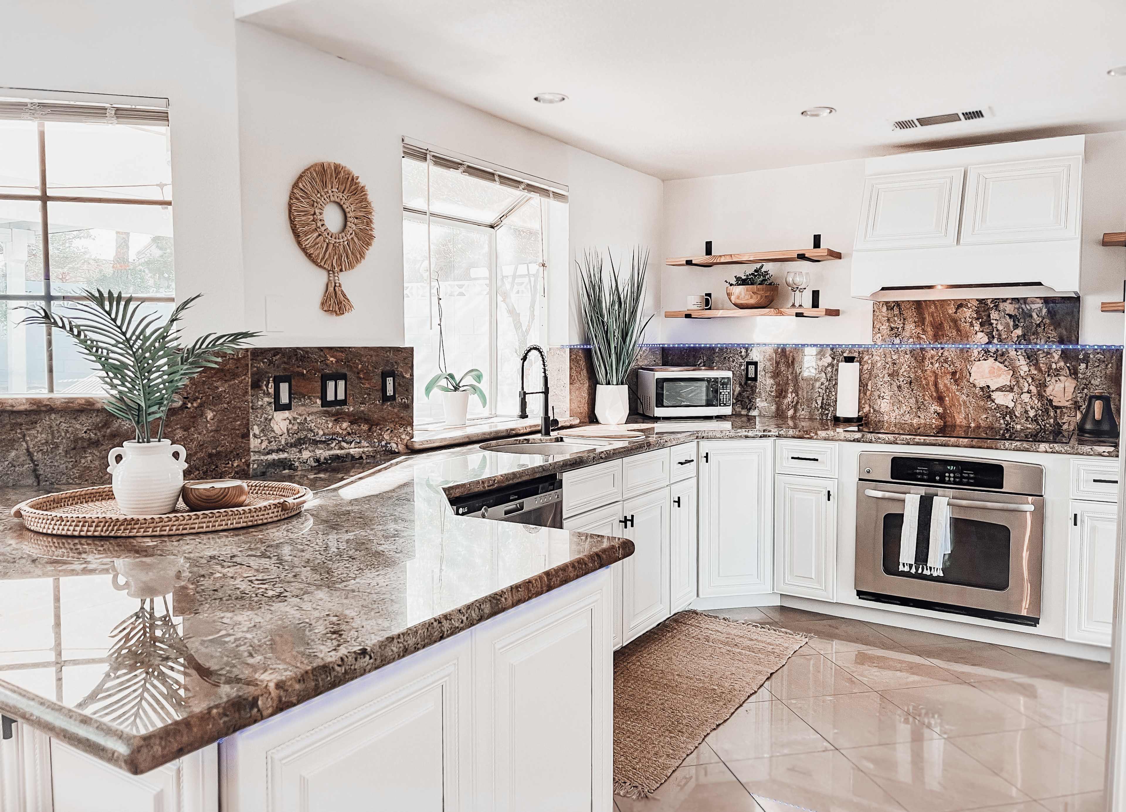 The kitchen features white cabinets, dark granite countertops, and natural light streaming through large windows.
