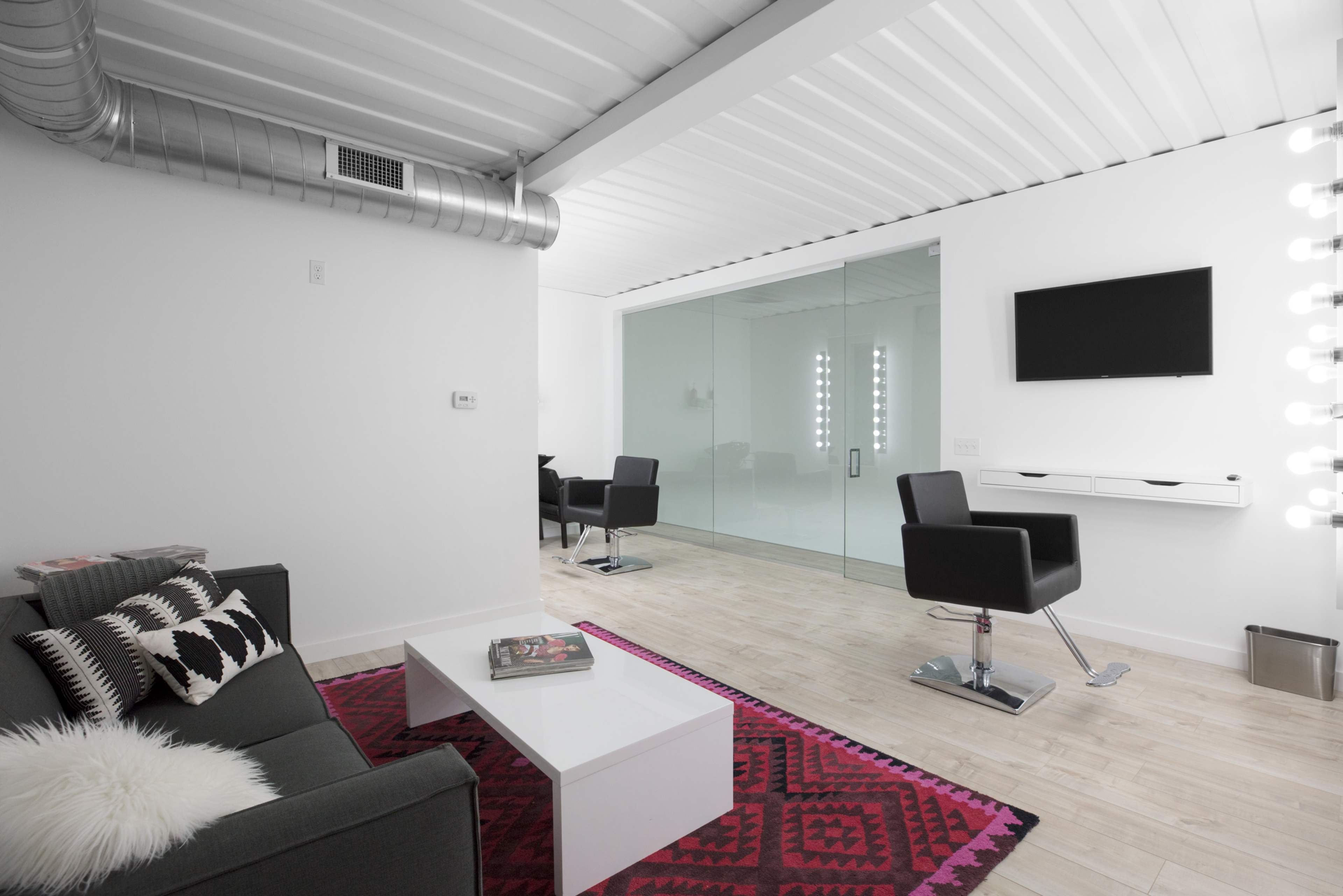 The room features a modern design with a glass-walled meeting area, minimalist furniture, and bright lighting.