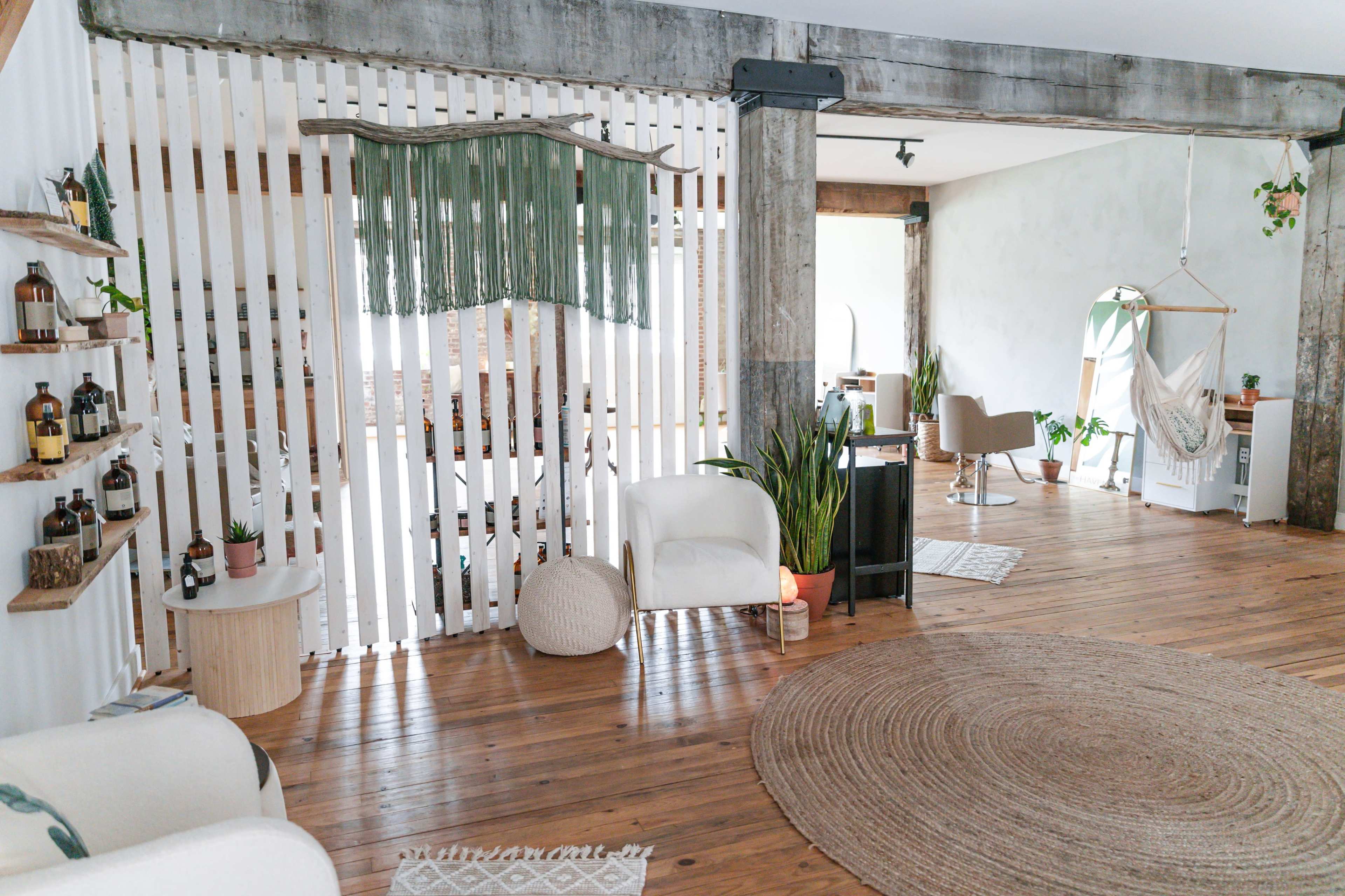 A spacious, modern interior featuring wooden flooring, plant decor, and a dividers with a textile hanging.
