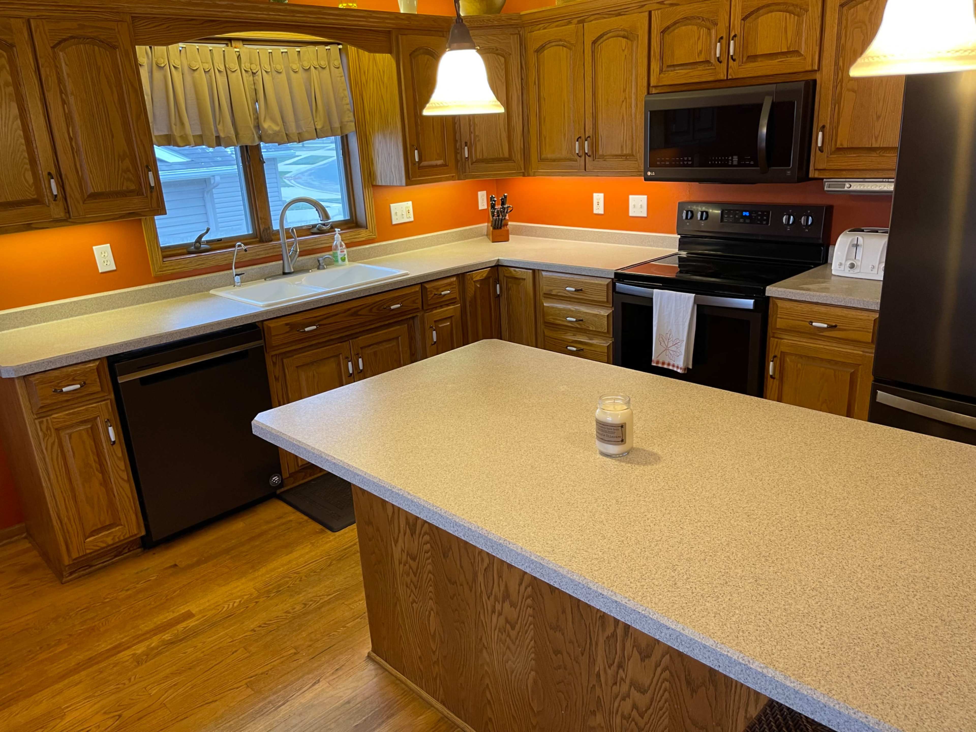 The kitchen features wooden cabinetry, a countertop island, and modern appliances, including a stove and dishwasher.
