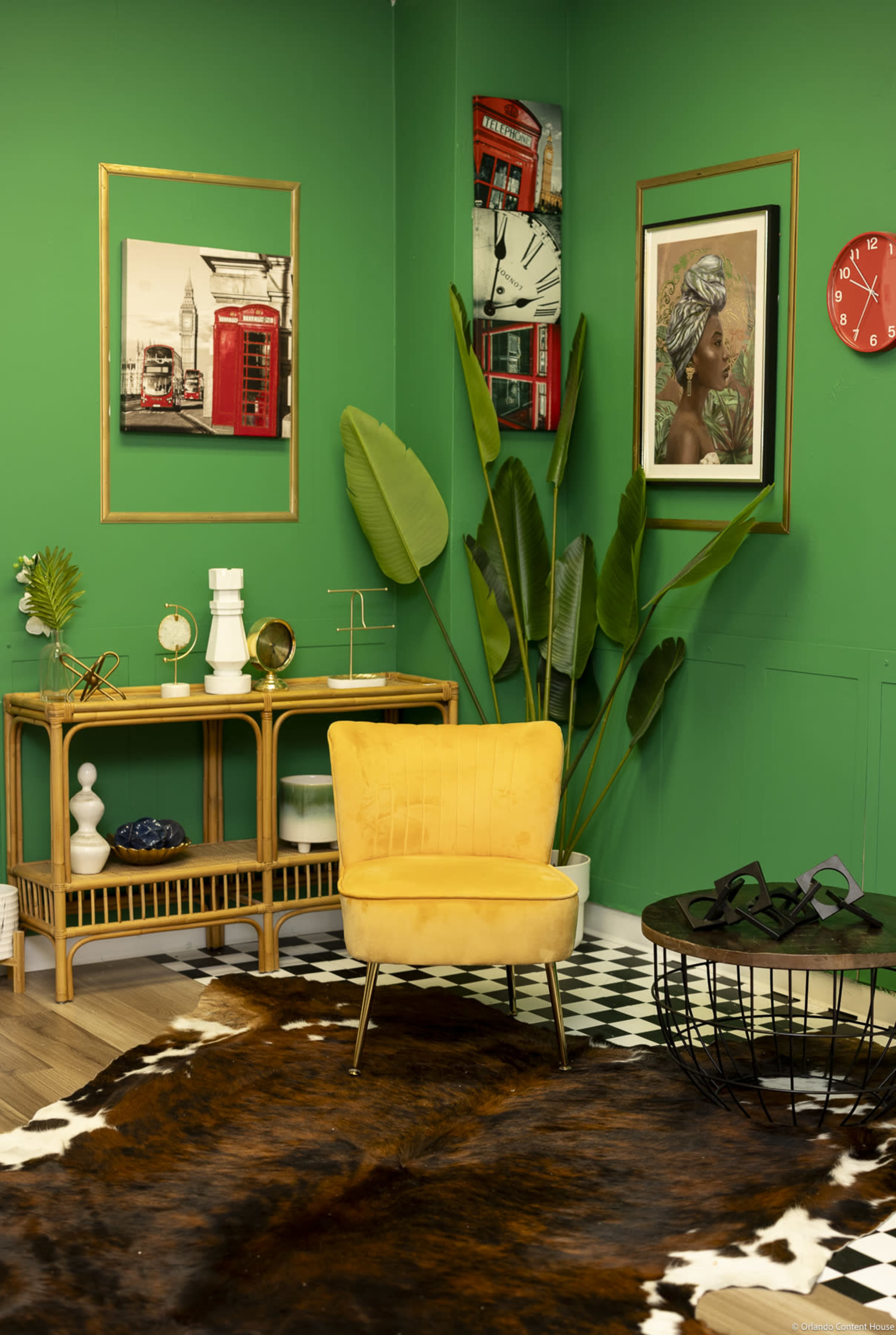 The image features a vibrant green room with a yellow chair, a wooden shelf displaying decor, and framed artwork on the walls, complemented by a cowhide rug and a large plant.