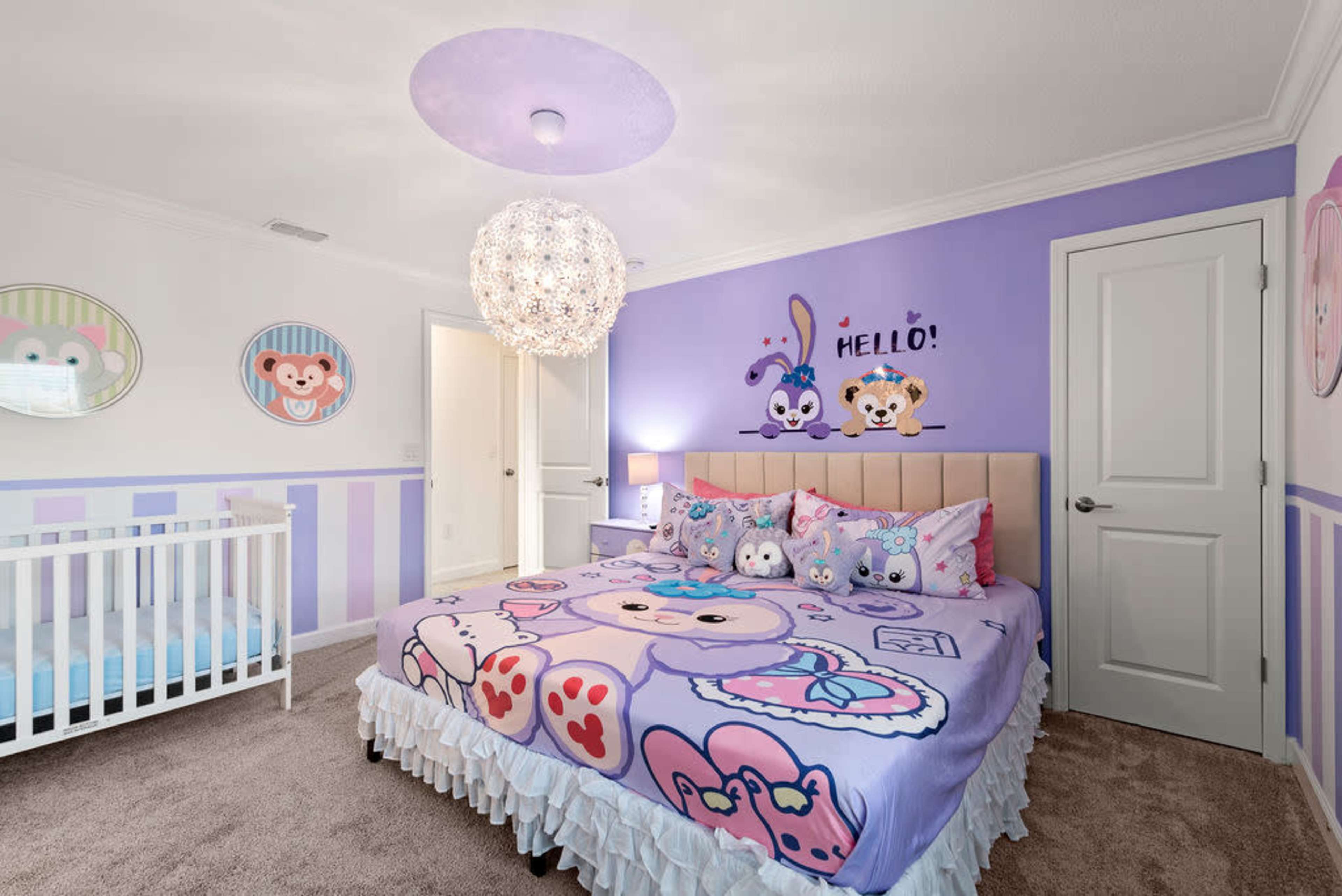 A children's bedroom features a crib, a large bed with character-themed bedding, and playful wall decor in purple and pastel colors.