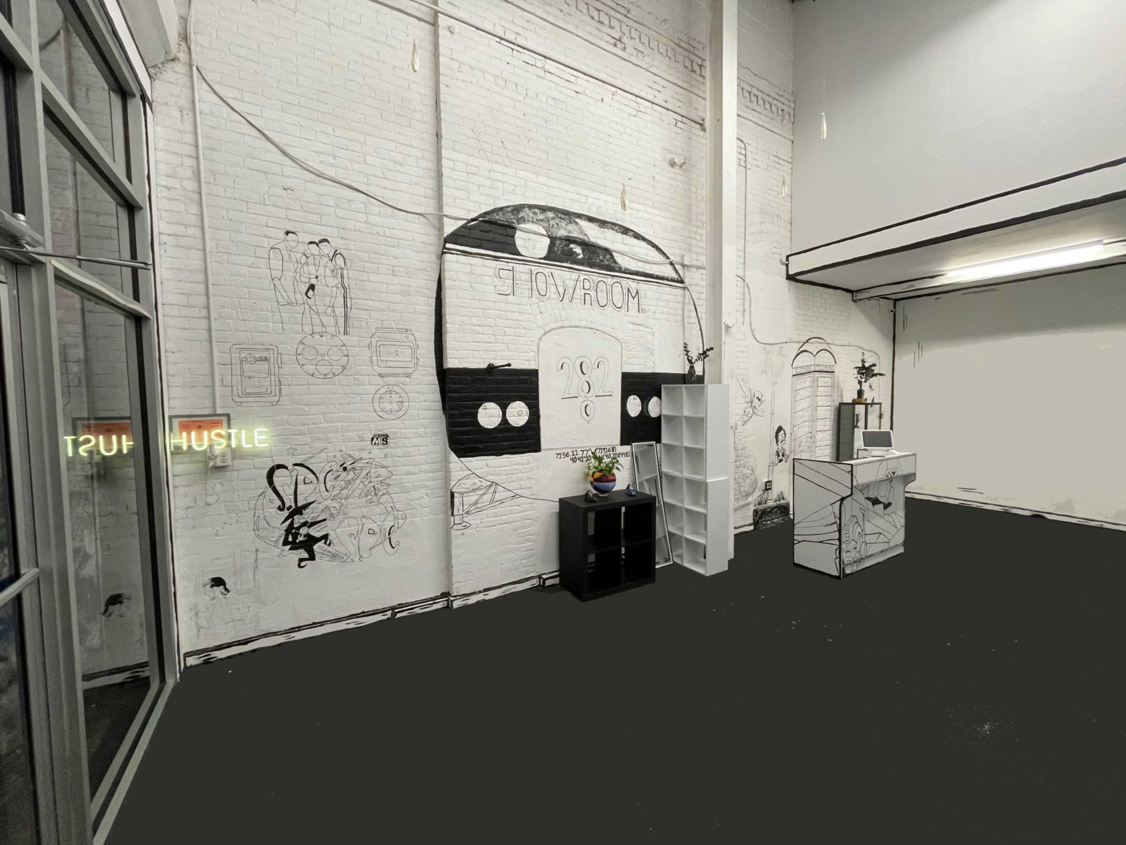 An empty room with white brick walls featuring a mural, a small potted plant on a table, and a bookshelf against the wall.