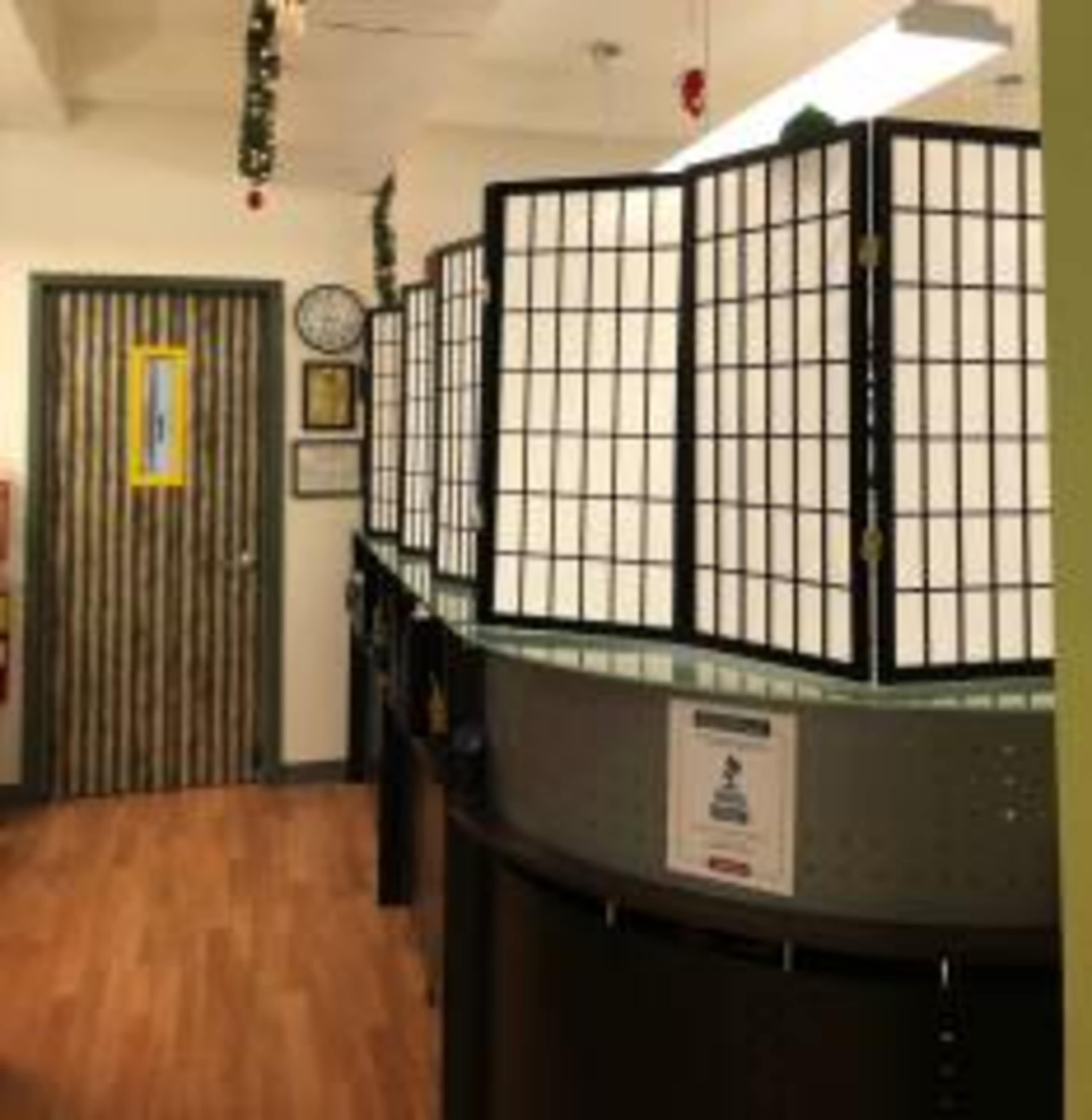 The image shows a hallway with a series of partition screens separating work areas, leading to a door at the end.