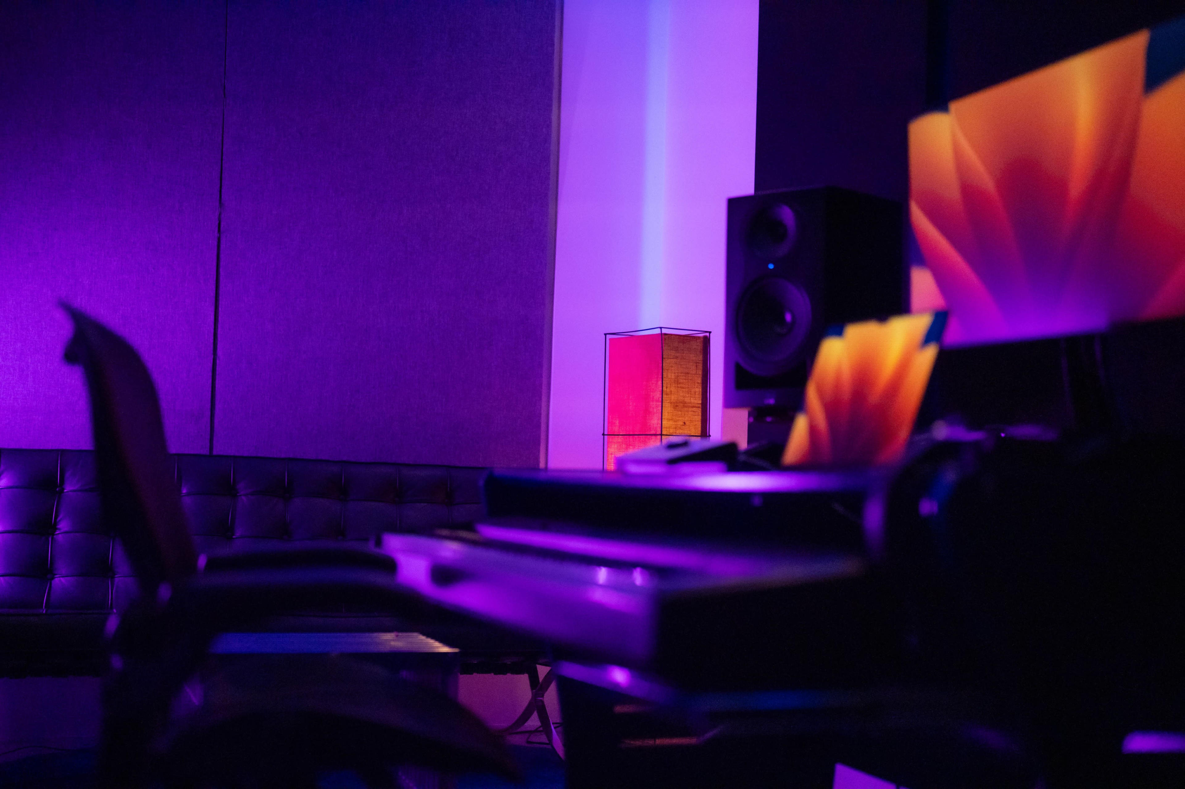 A music studio with a black couch, sound equipment, and colorful lighting.