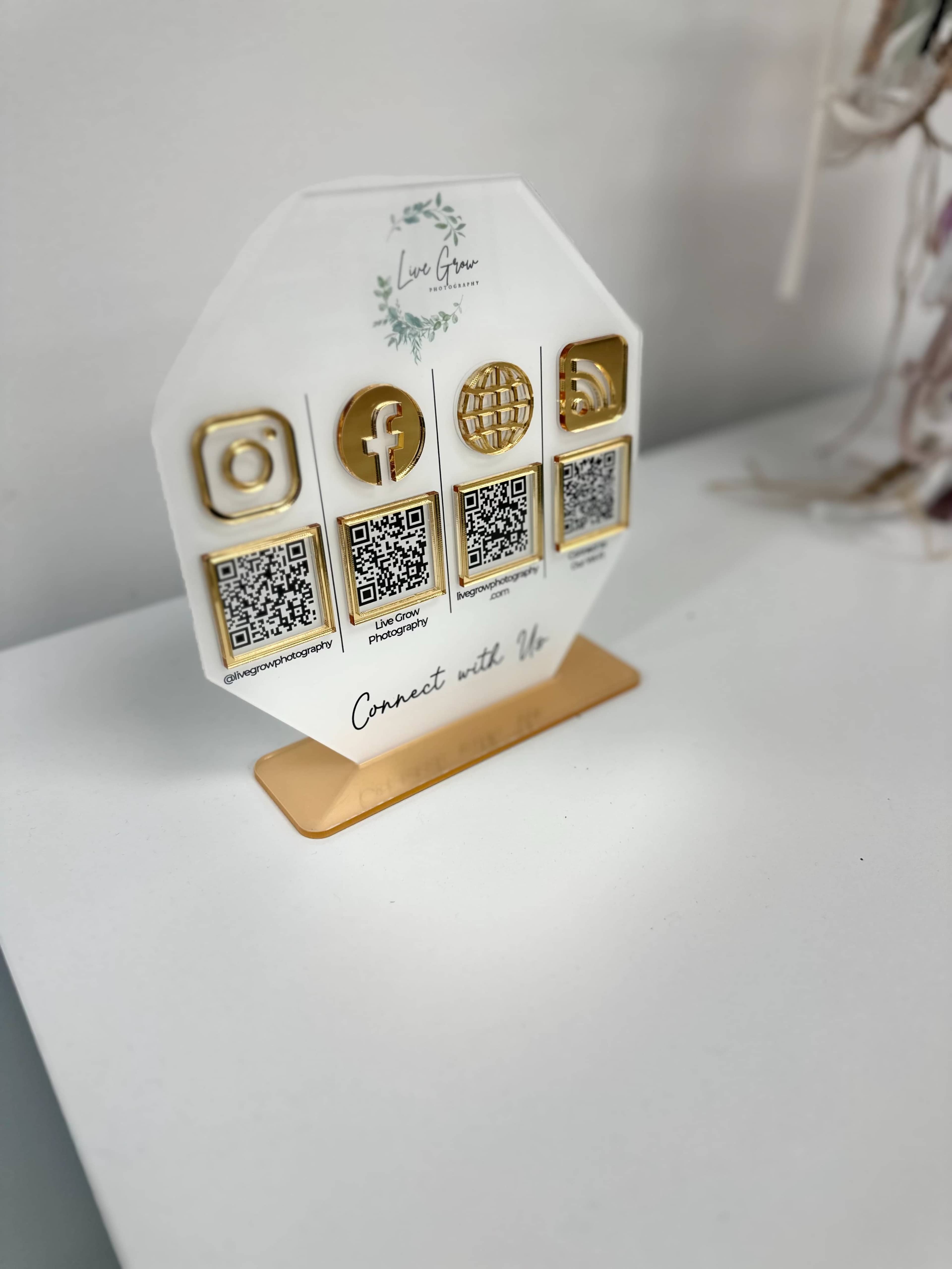 A display stand featuring social media icons and QR codes arranged in a hexagonal shape on a white surface.