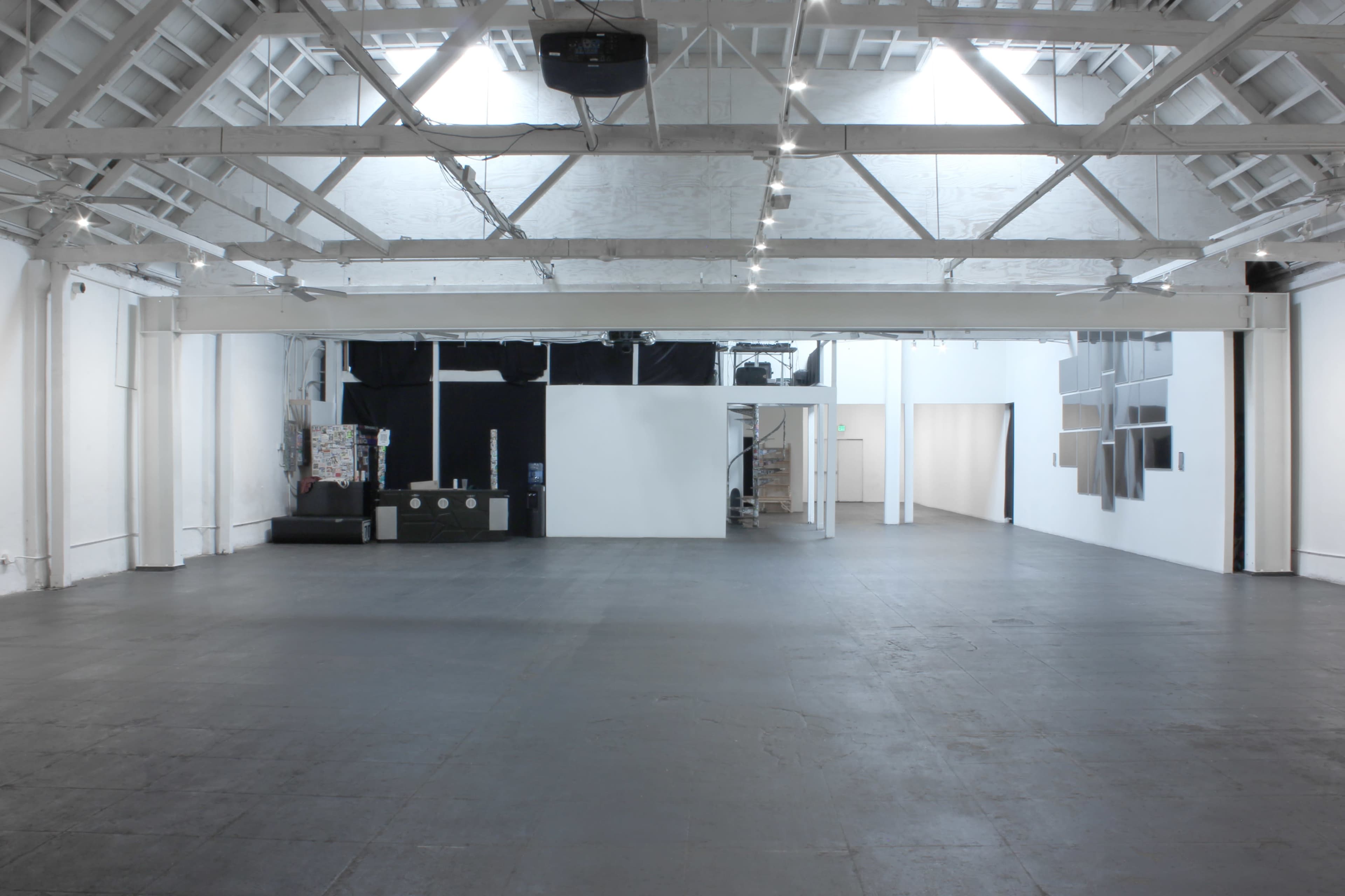 A spacious, empty art gallery with high ceilings and white walls.
