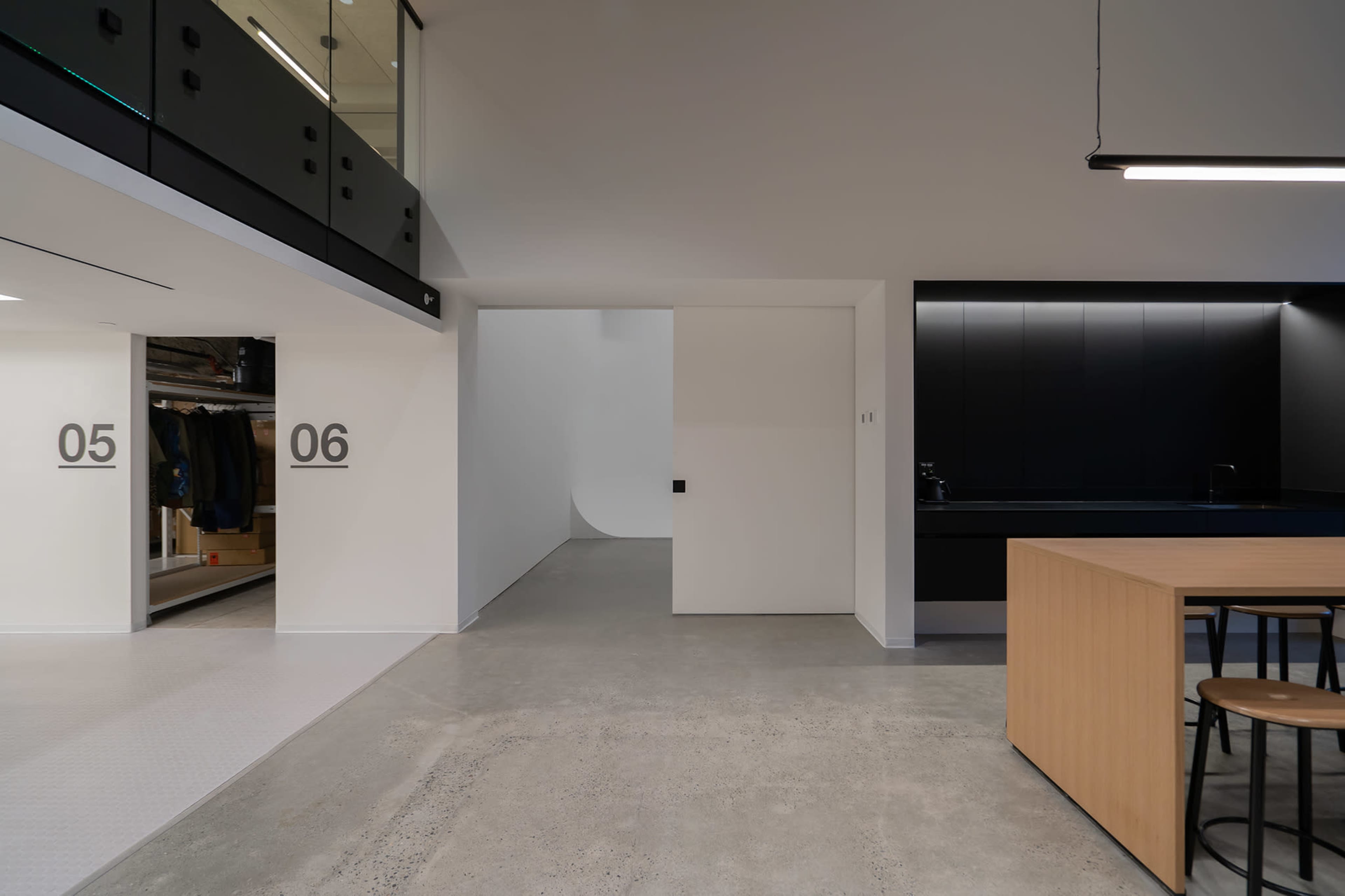 A modern interior space with a minimalist design, including a kitchen area, a closet labeled "05," and a wall with a hidden door labeled "06."