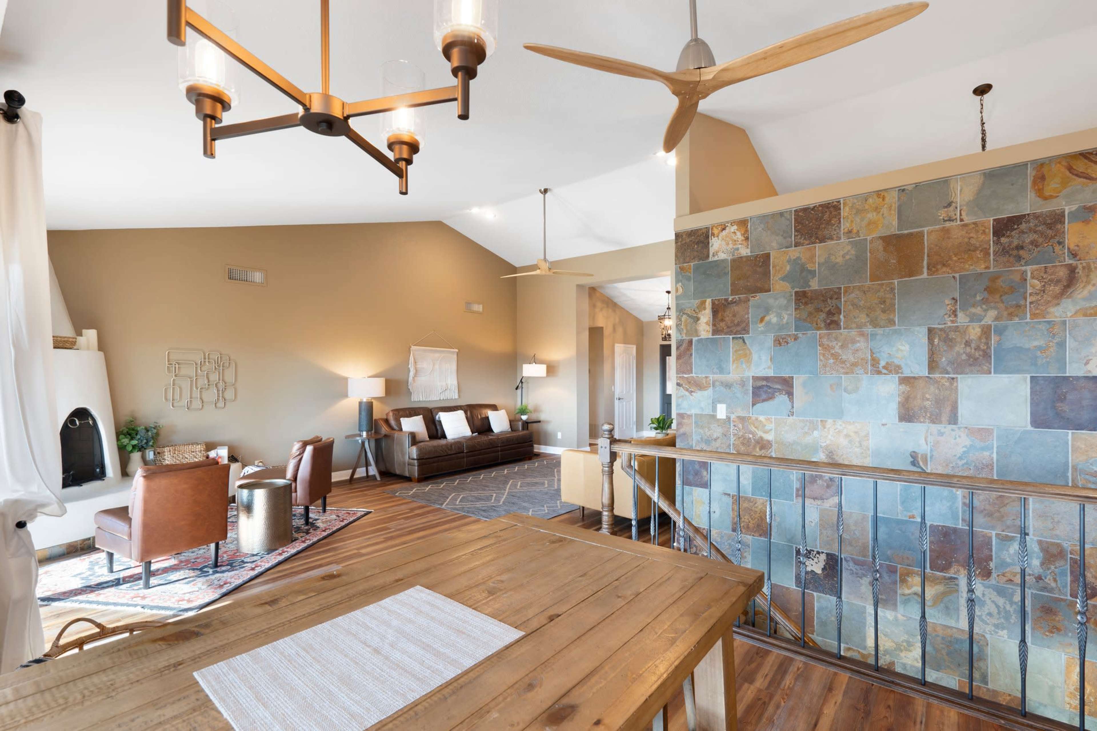 A spacious, modern living area with a combination of a wooden dining table, a stone accent wall, and comfortable seating arrangements.