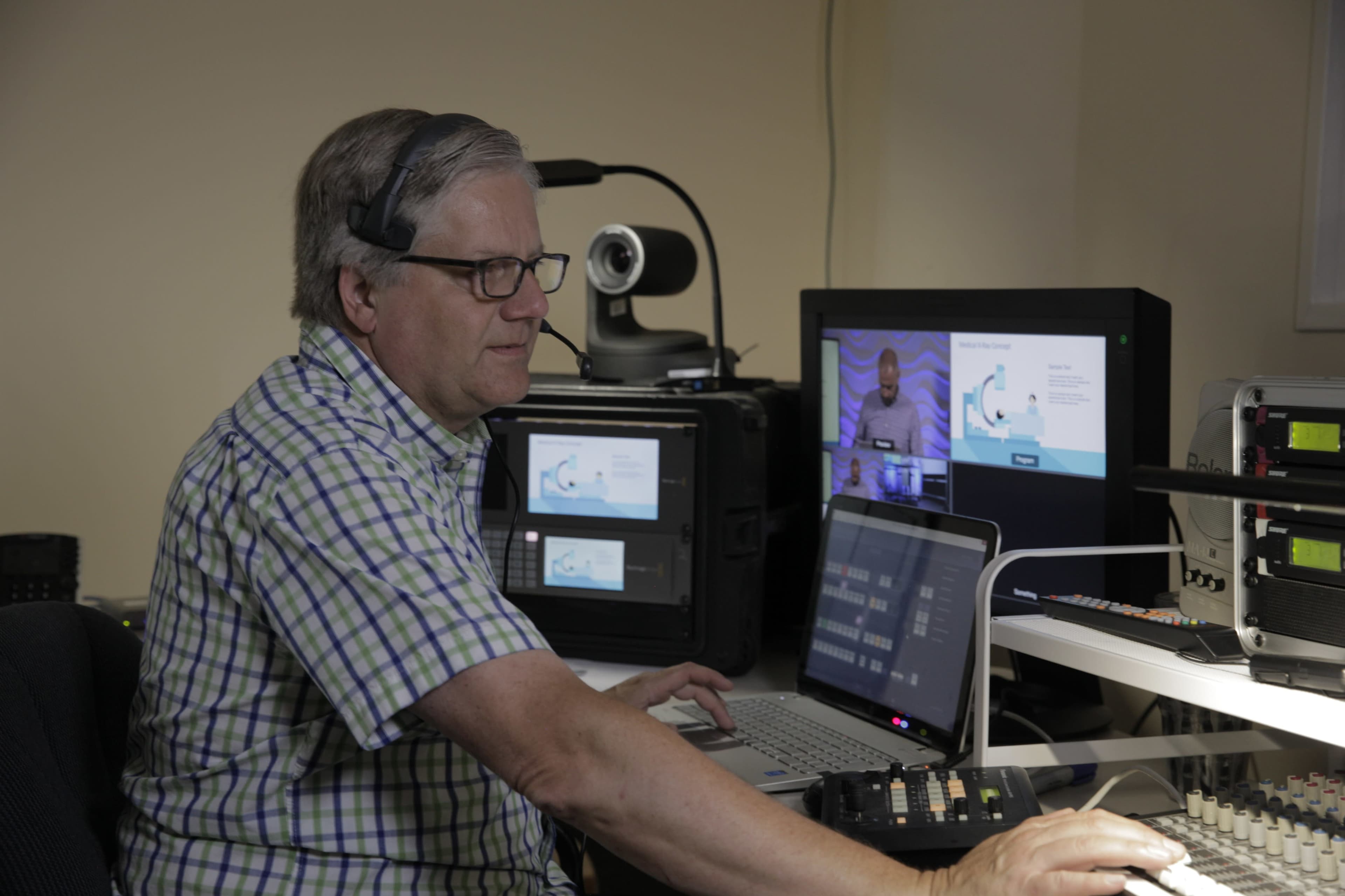 A man is operating video equipment and managing a live stream in a studio setting.