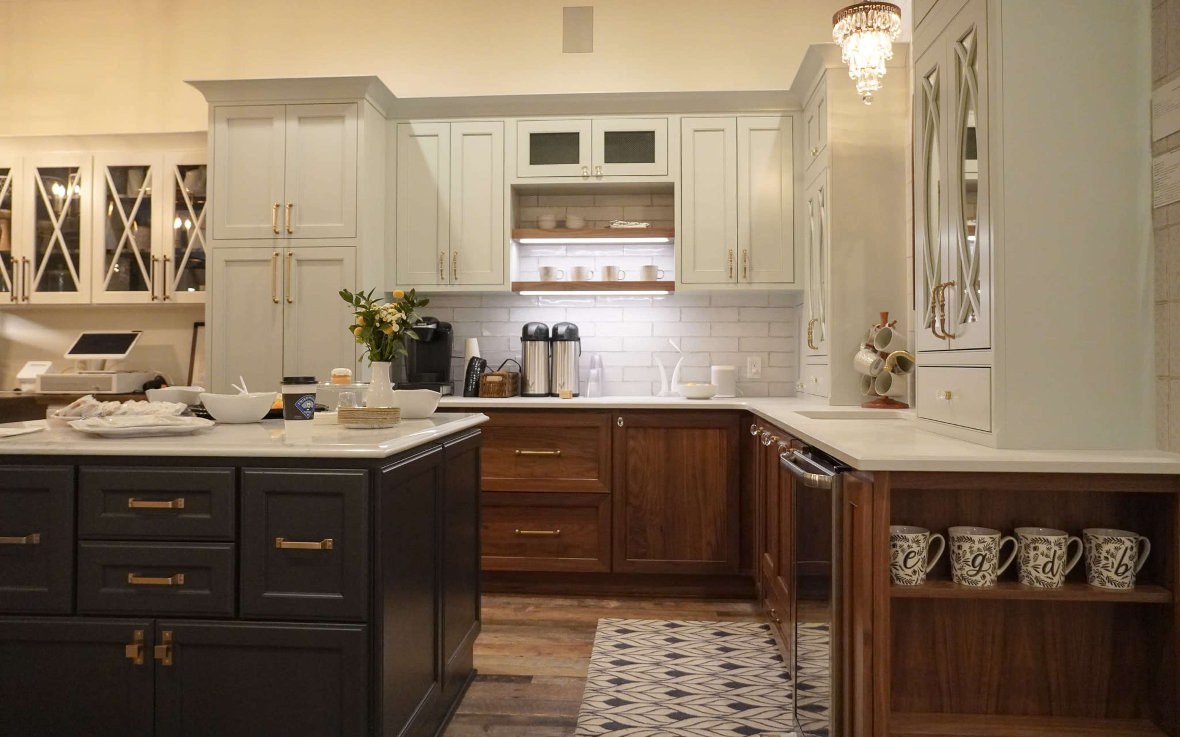 A modern kitchen with light gray and dark wood cabinets, a large island, and a decorative rug.