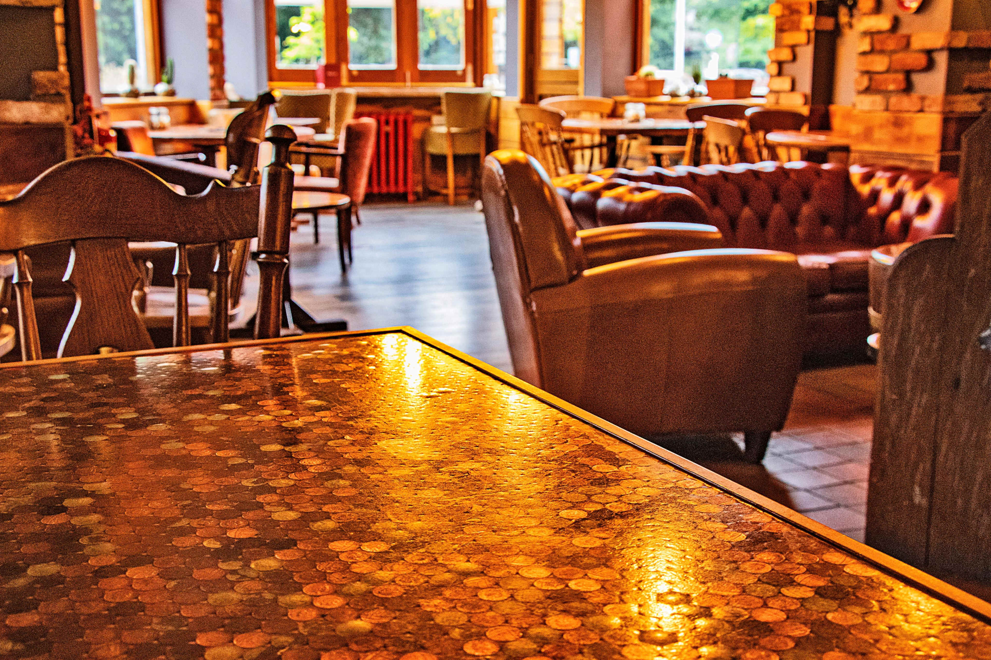 A cozy cafe interior with a table made of coins and various seating options in the background.