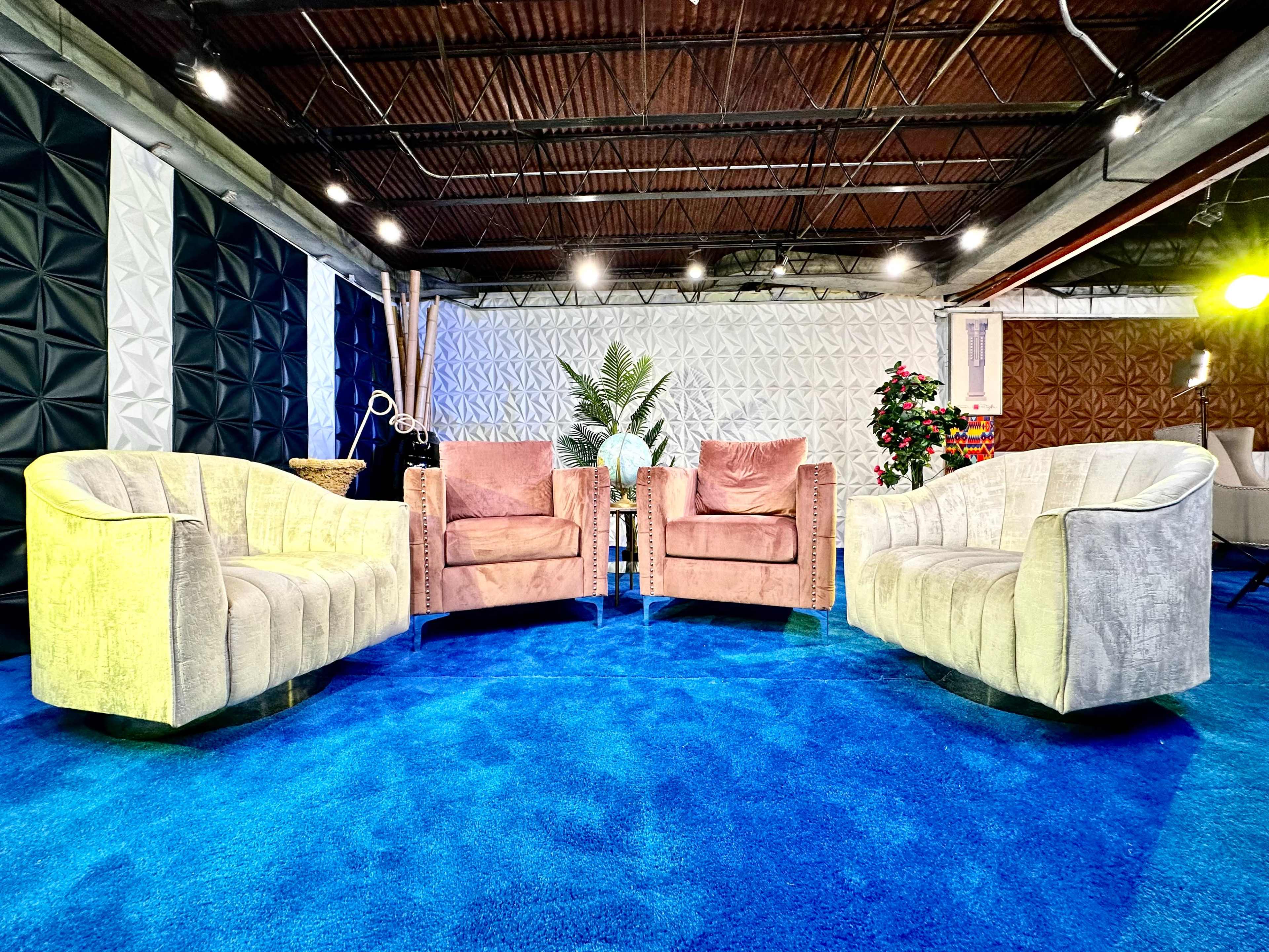 A seating area with two armchairs positioned across from each other on a blue carpet, surrounded by textured walls and greenery.