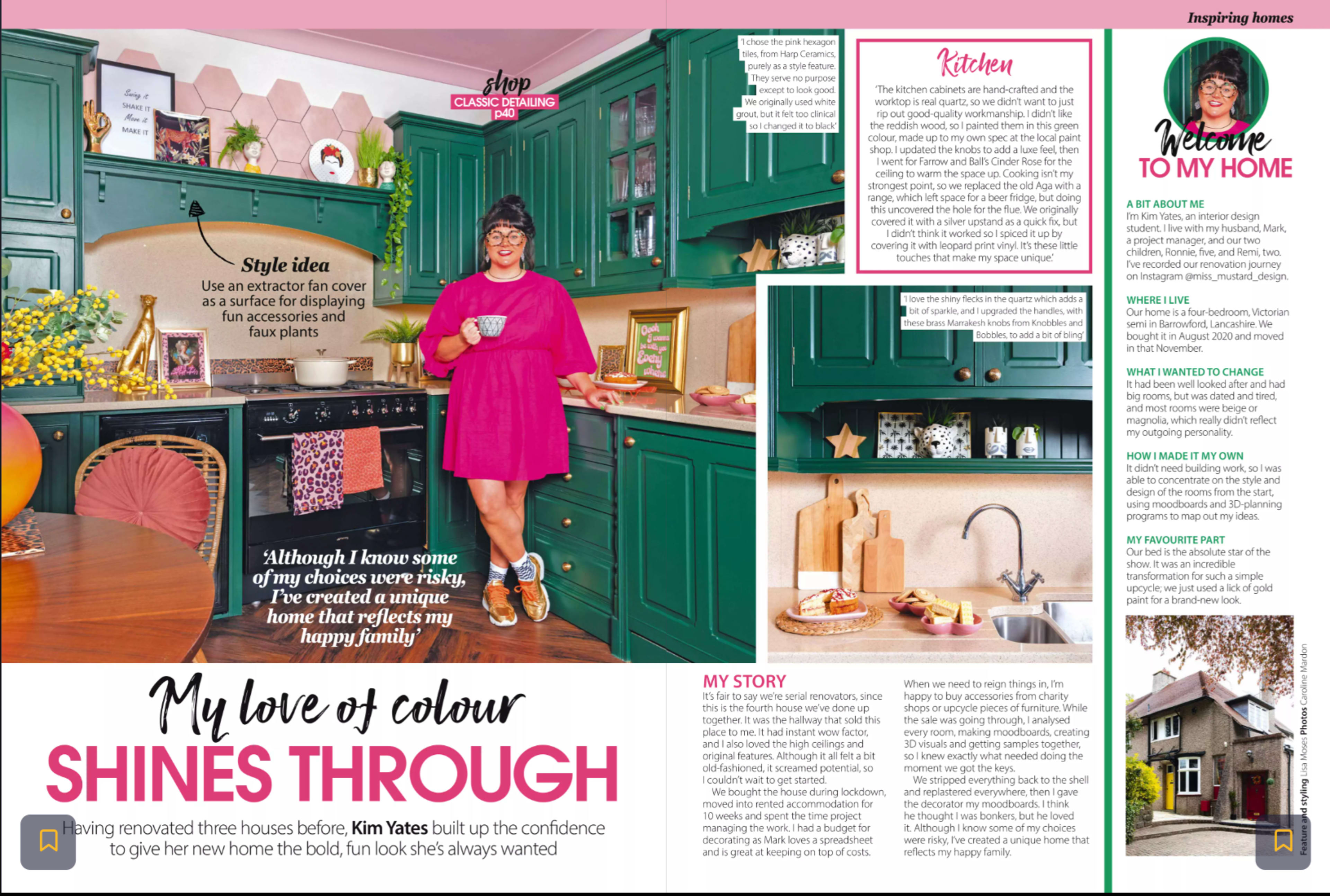 A bright kitchen with dark green cabinetry, a woman in a pink dress, and various decorative elements showcasing a vibrant interior design style.