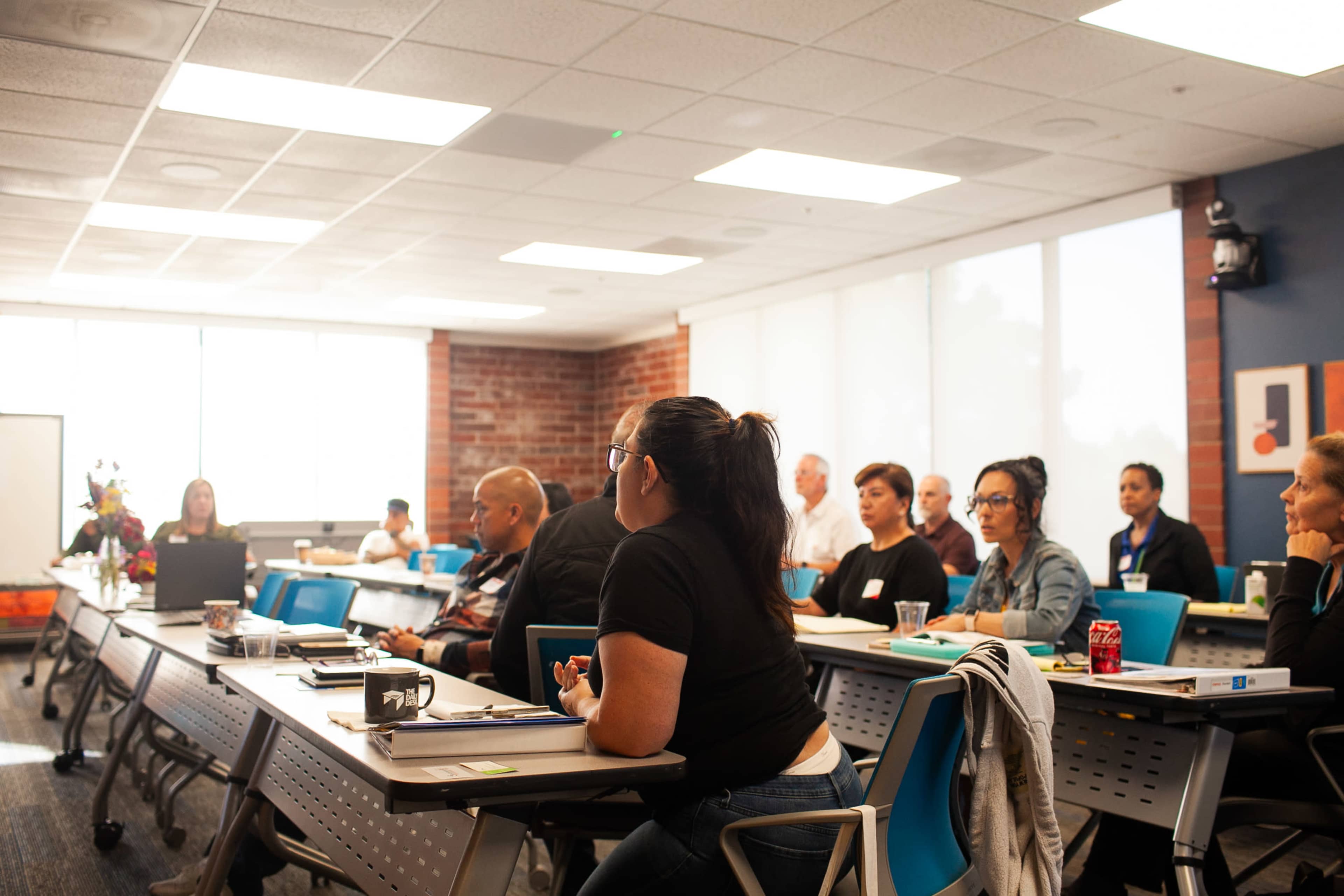 A classroom filled with students attentively listening to a speaker at the front.