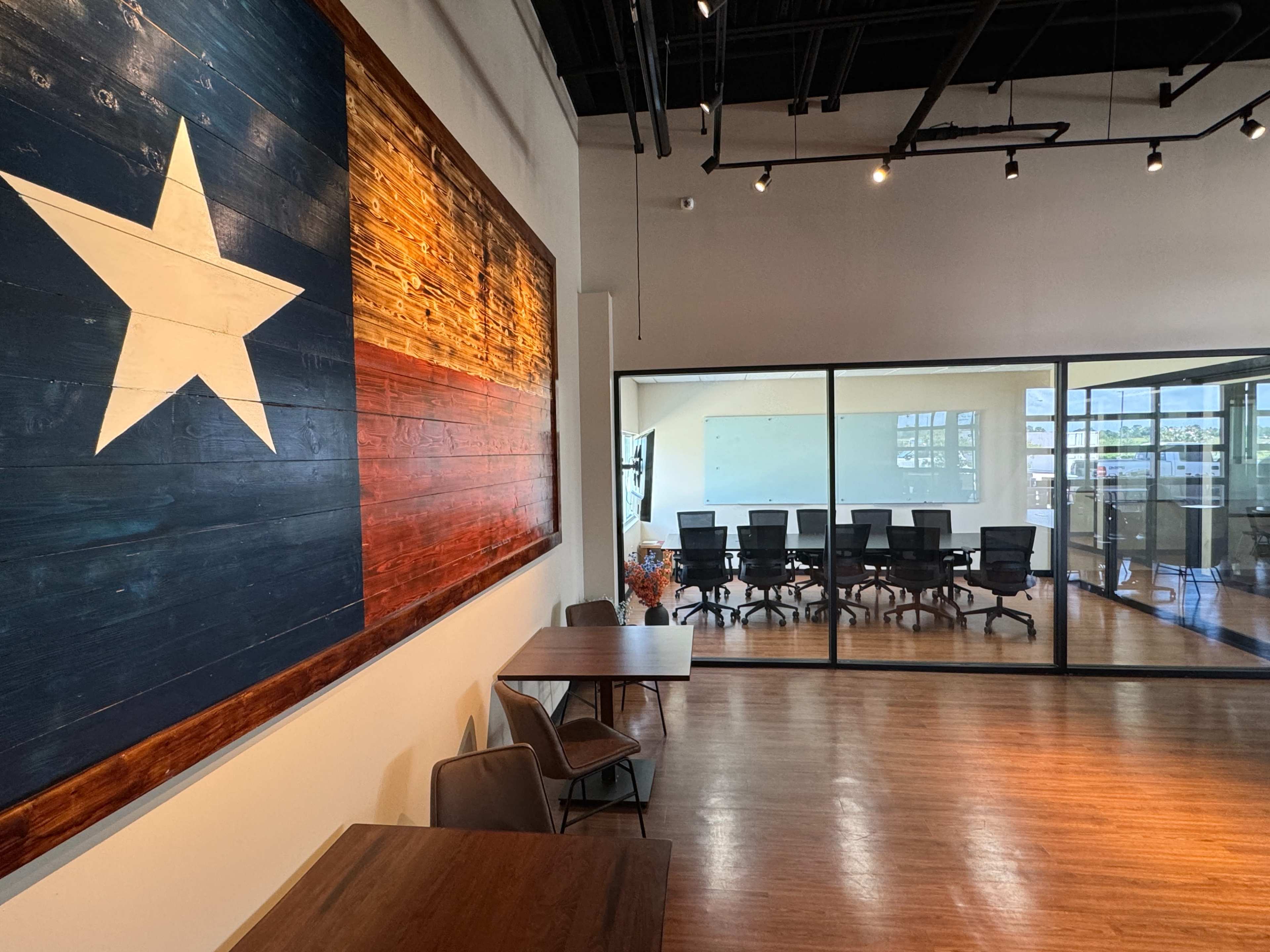 A room with a large wooden wall art of the Texas flag and a glass-walled conference room visible in the background.