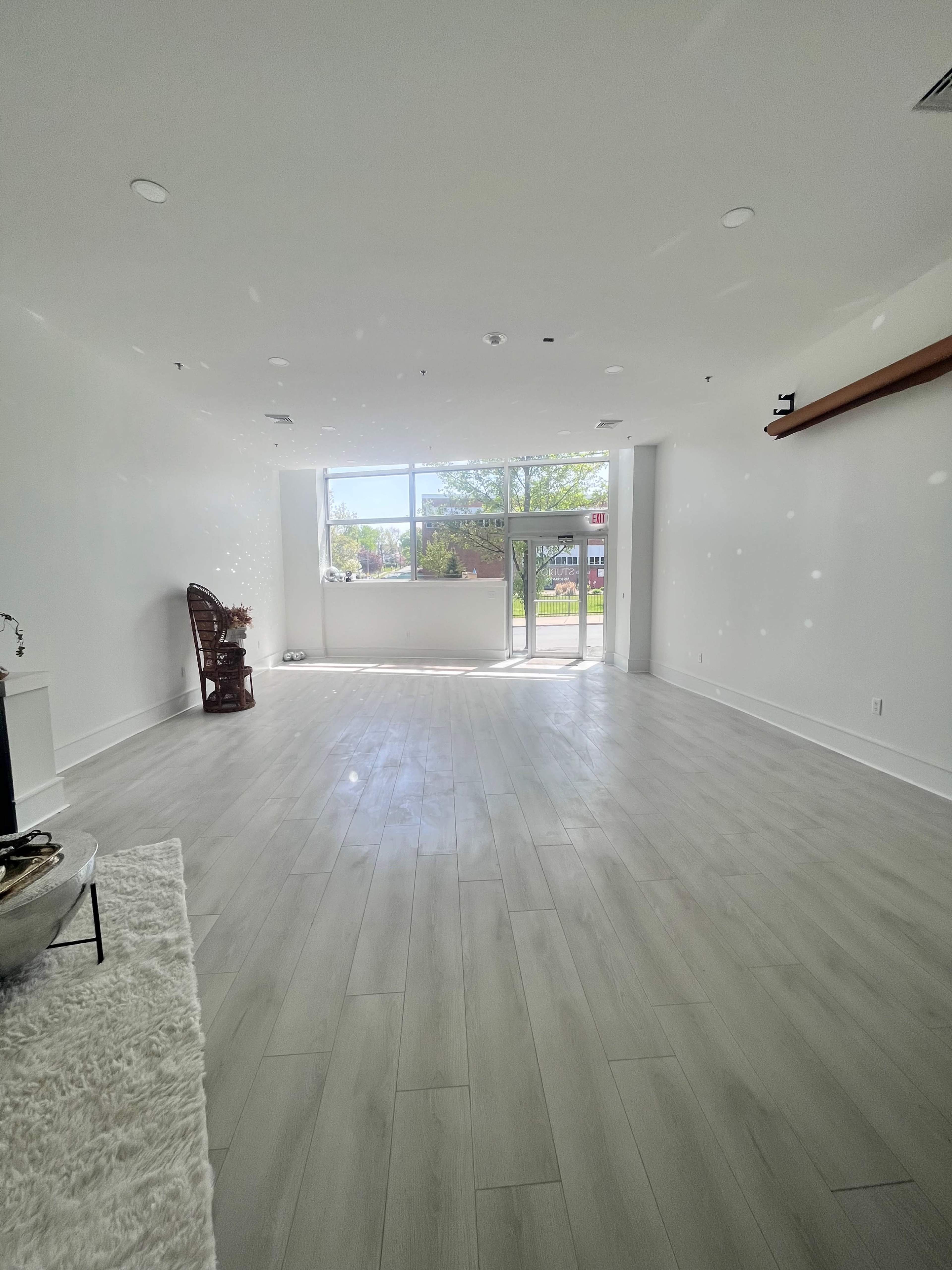 A spacious, empty room with large windows letting in natural light and a door leading outside.
